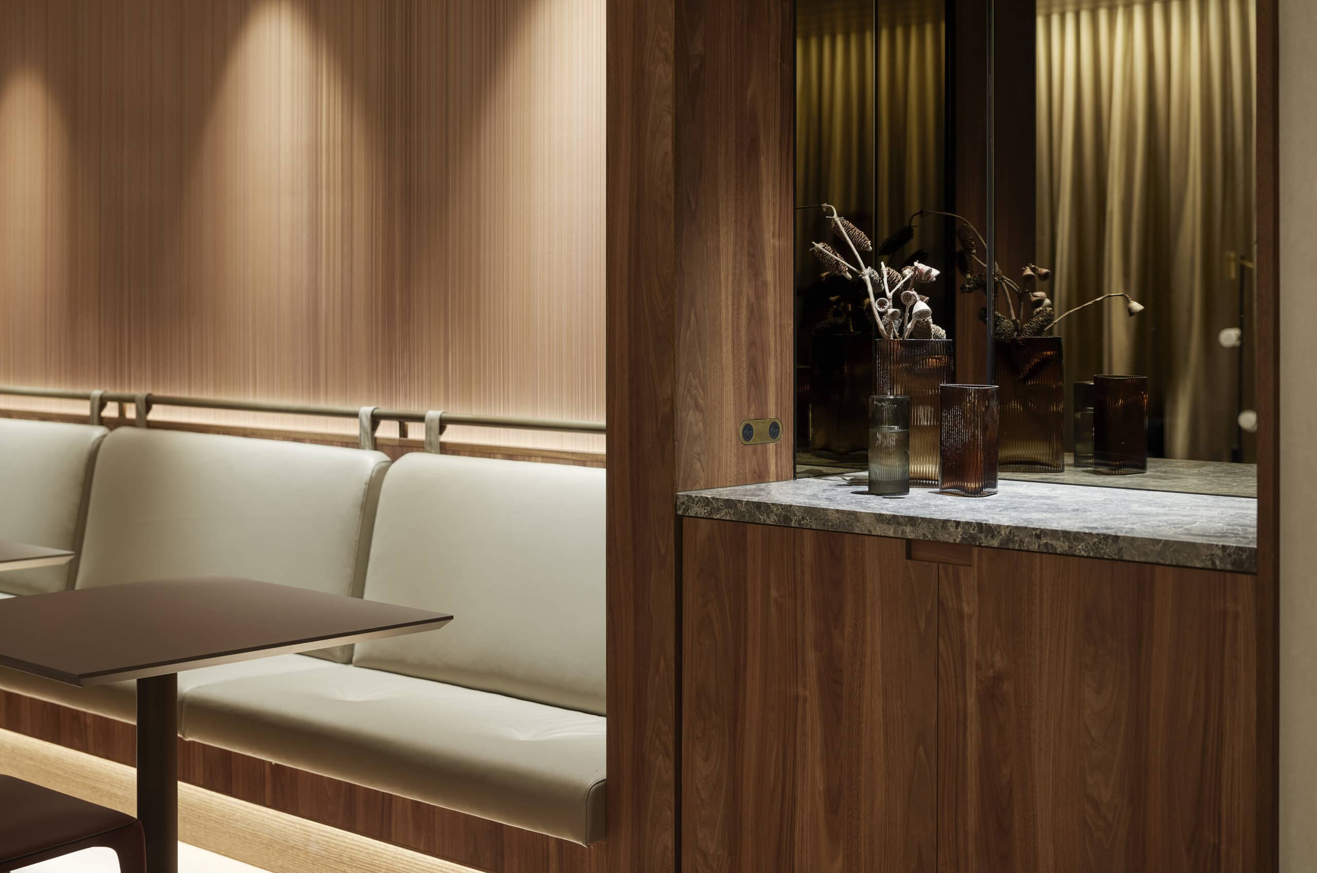 Upholstered lounge seating and timber joinery beside a stone-topped display recess.