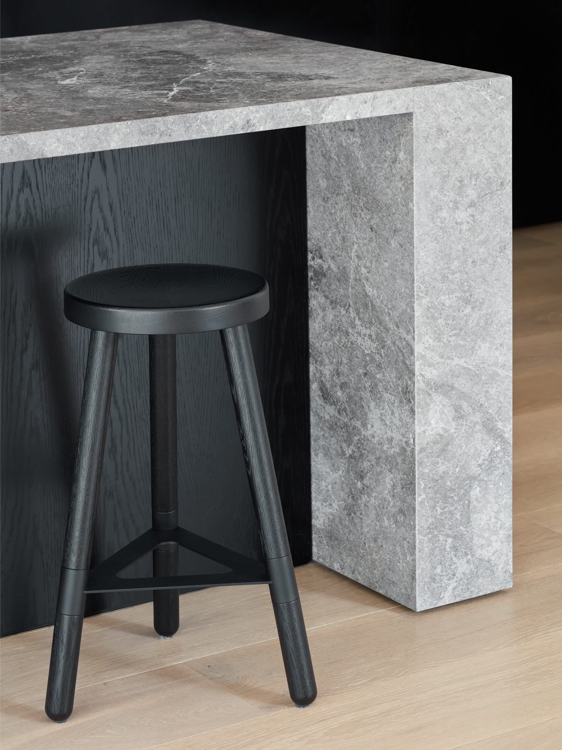 Dark stool tucked beneath a grey stone kitchen island with a waterfall end.