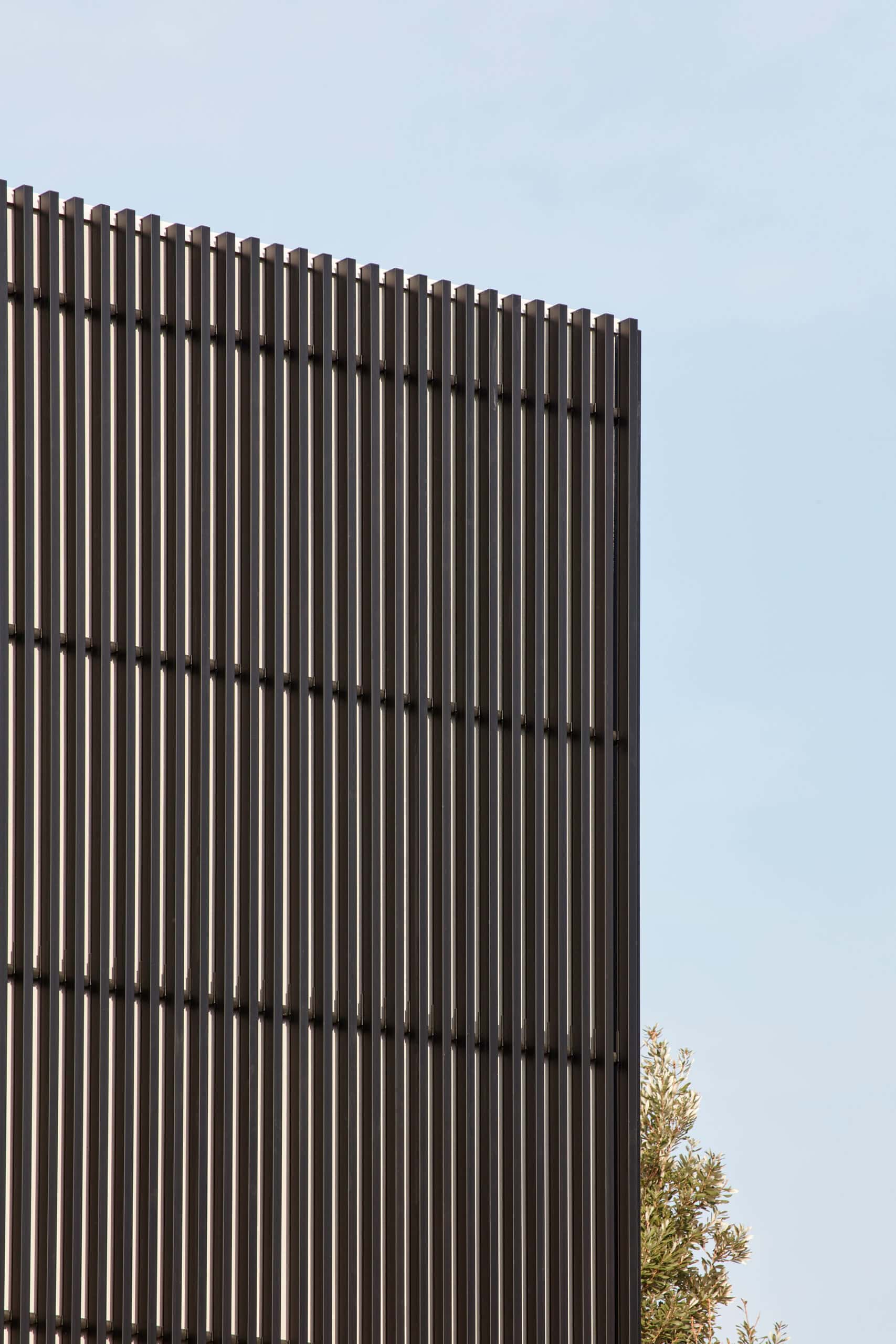 Close view of closely spaced vertical facade fins against a pale sky.