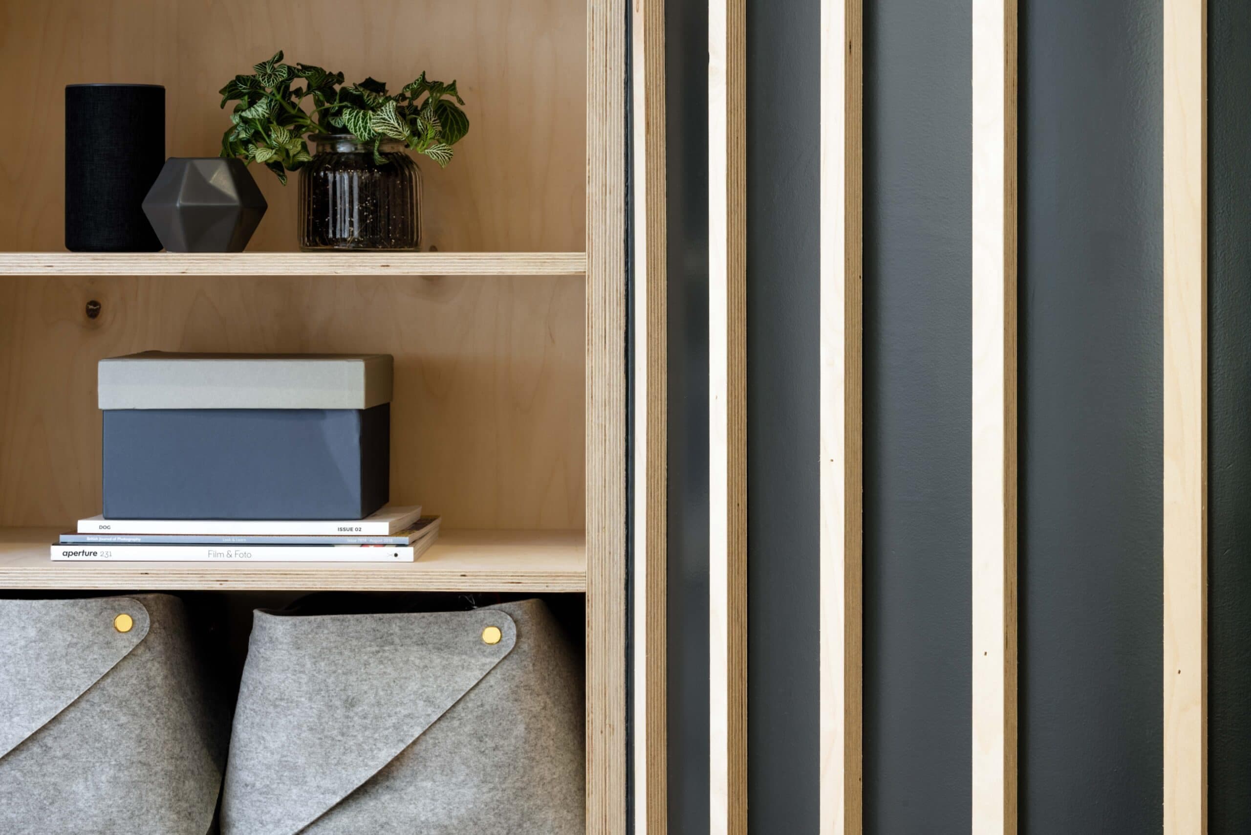 Built-in timber shelving with felt storage baskets beside a vertical slatted screen.