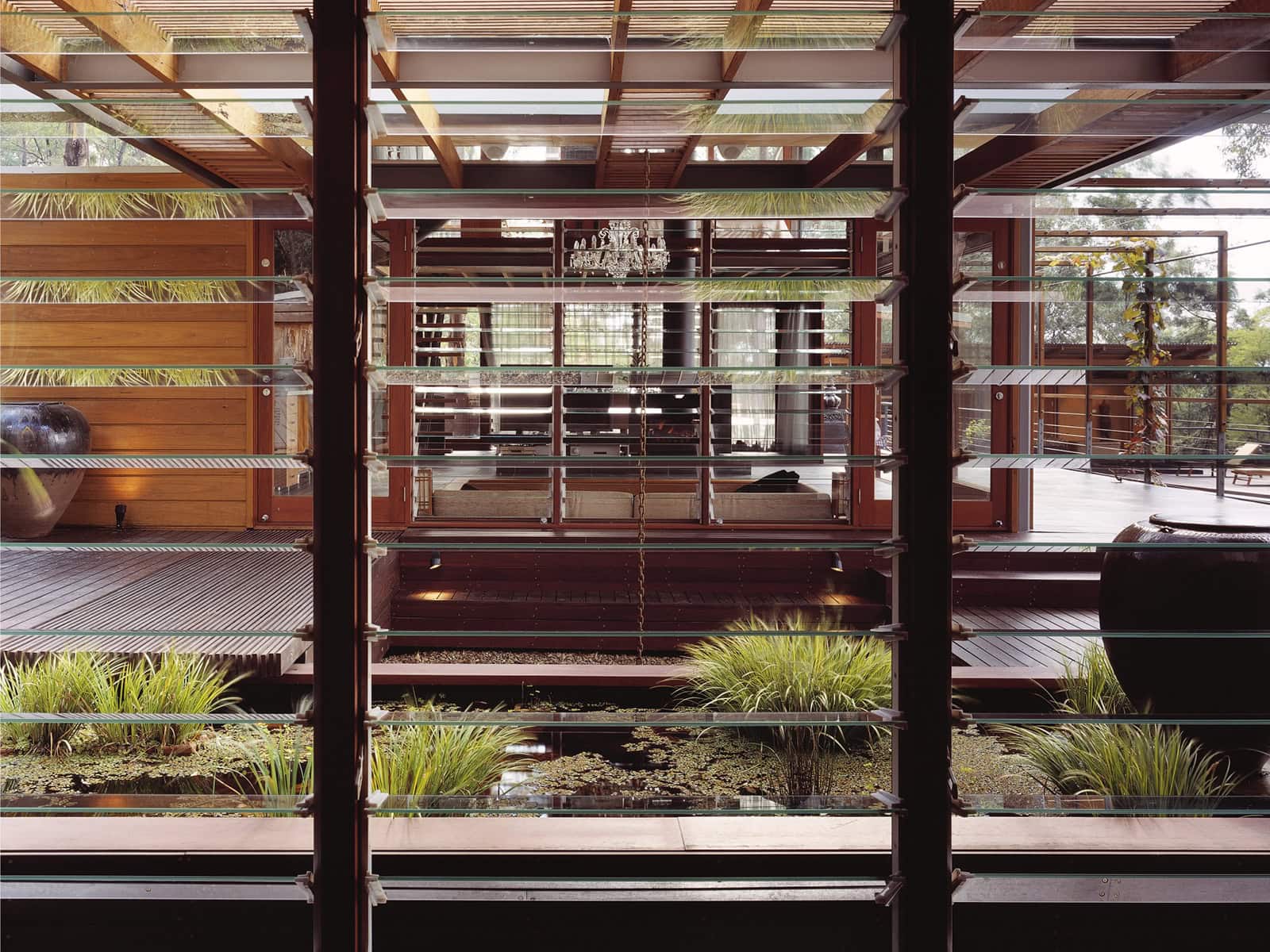 Planted courtyard and timber decking viewed through horizontal bedroom louvres.
