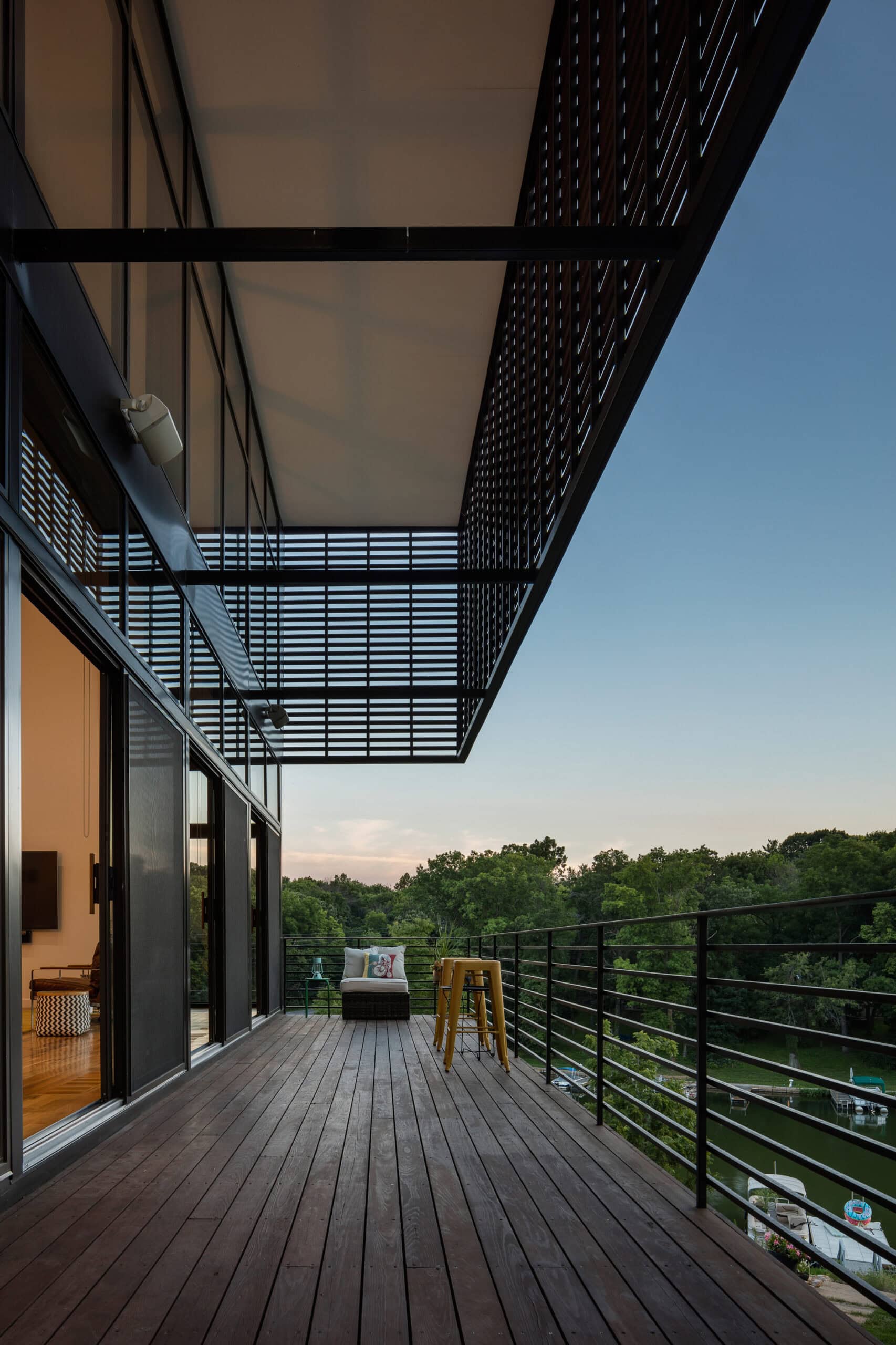 Timber terrace with a metal balustrade beneath a projecting screened upper storey.
