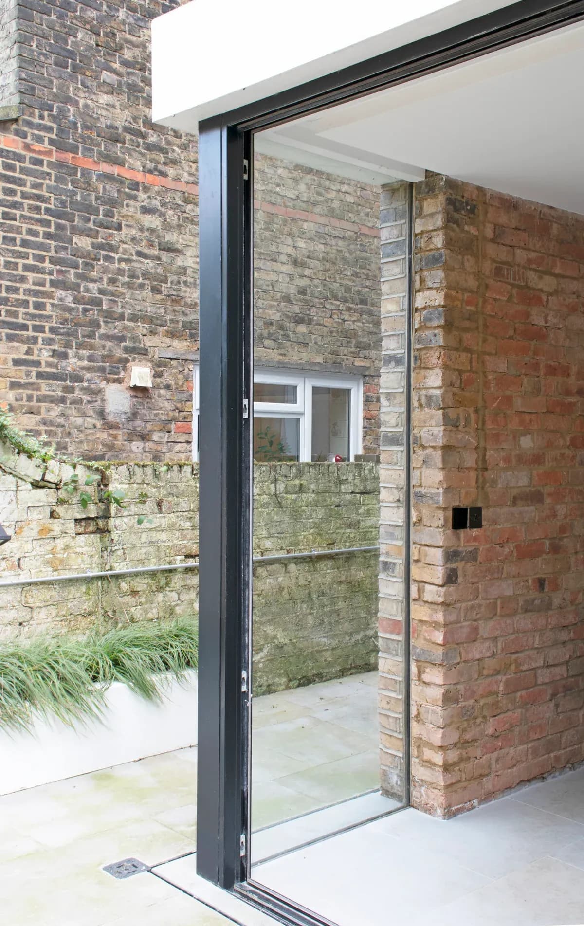 A frameless glazed corner connects the rear extension with its garden.