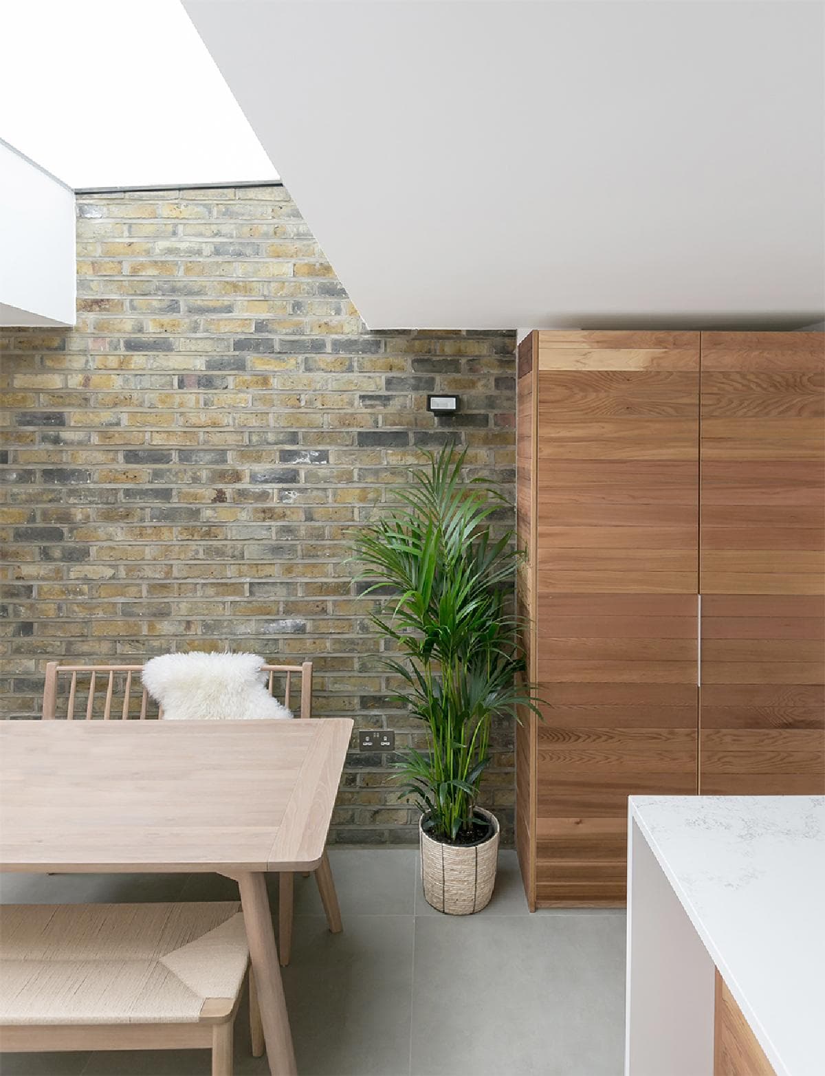 A rooflight meets the brick wall above the dining table at House in Archway.