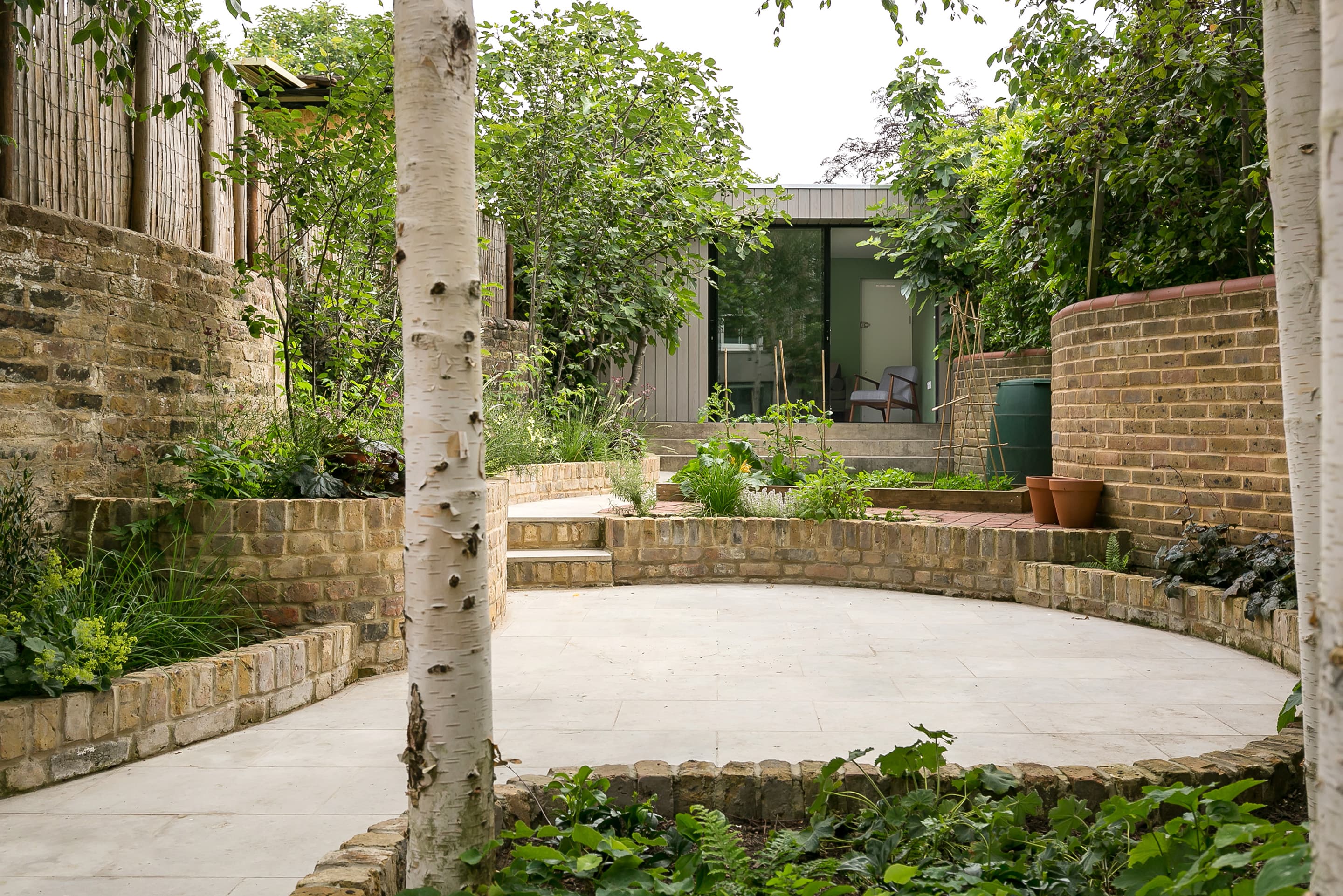 Planting and curved brick edges shape the courtyard between the two additions.