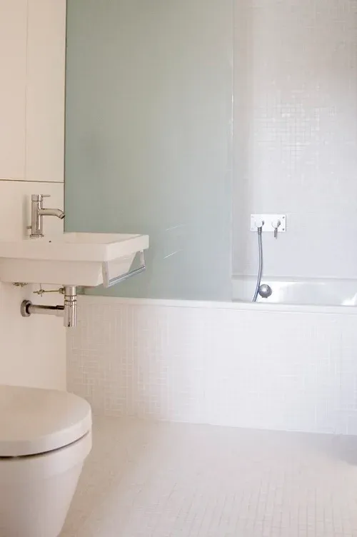 A mirror and white fittings keep the compact bathroom visually simple.