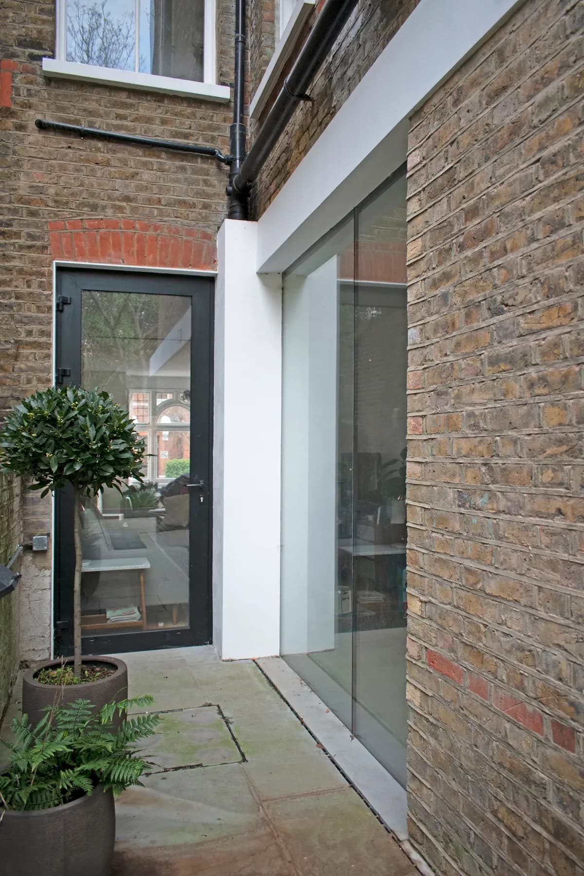 The rear extension’s white plane continues across the brick elevation.