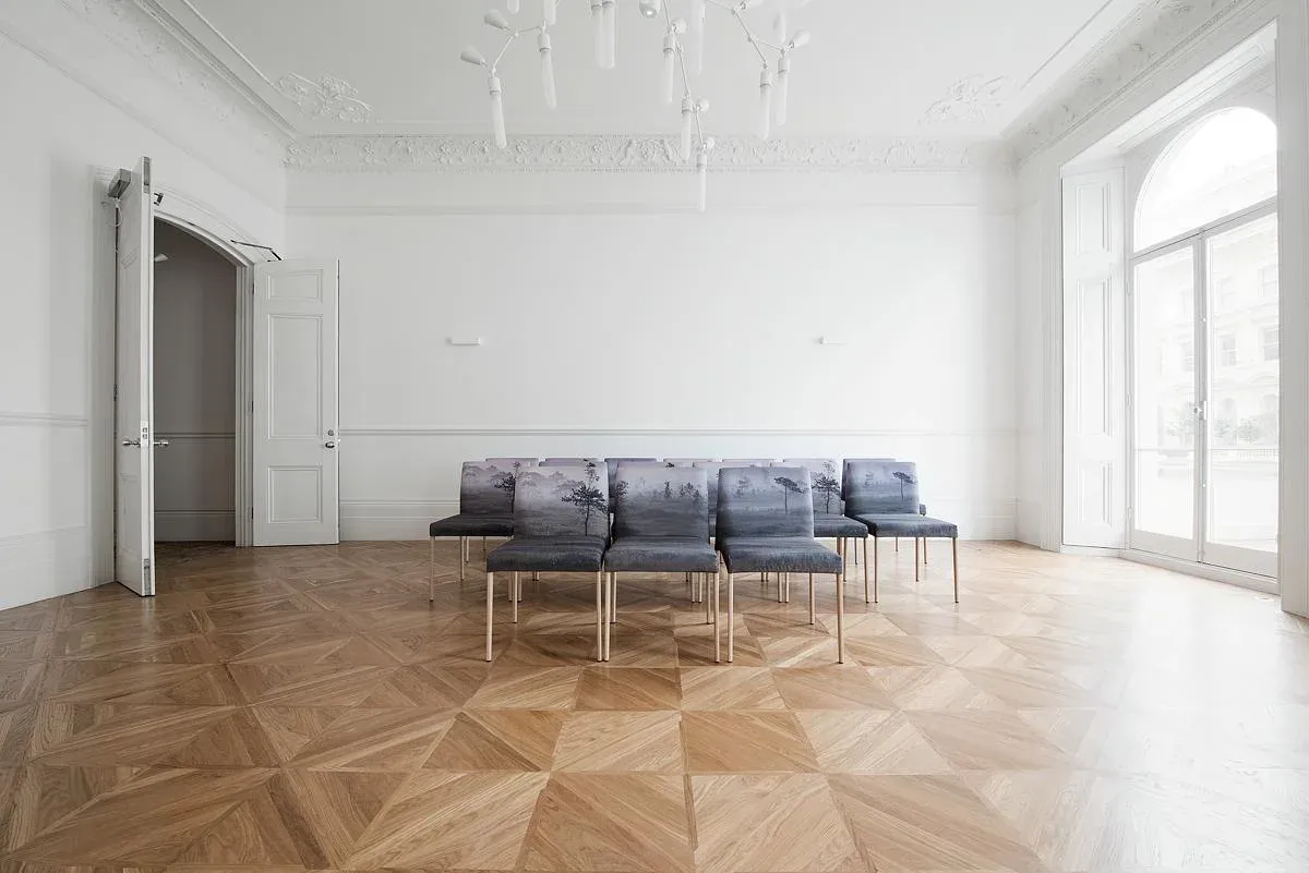 Grey seating is framed by tall windows and the patterned timber floor.