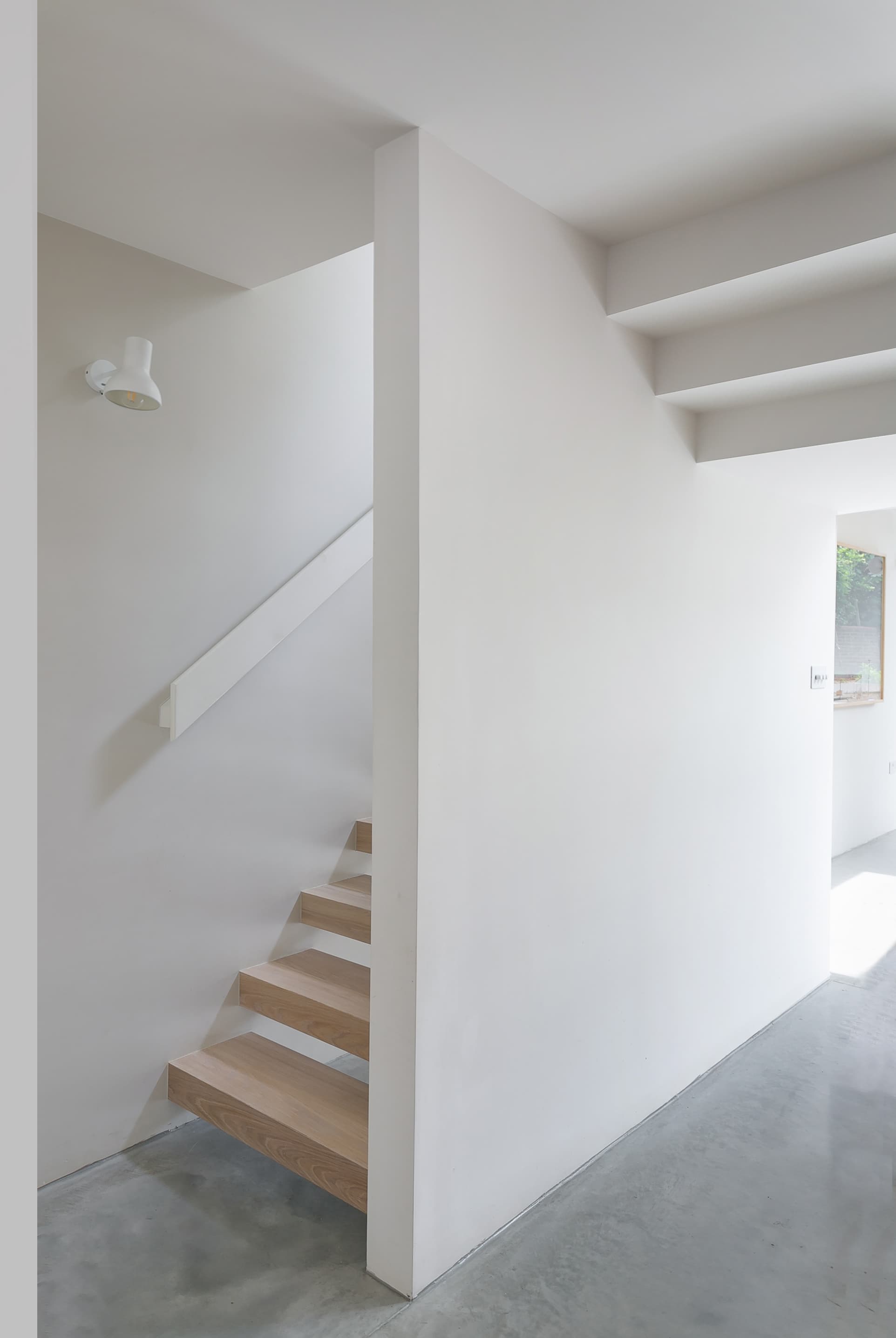A white blade wall separates the open timber stair from the living space.