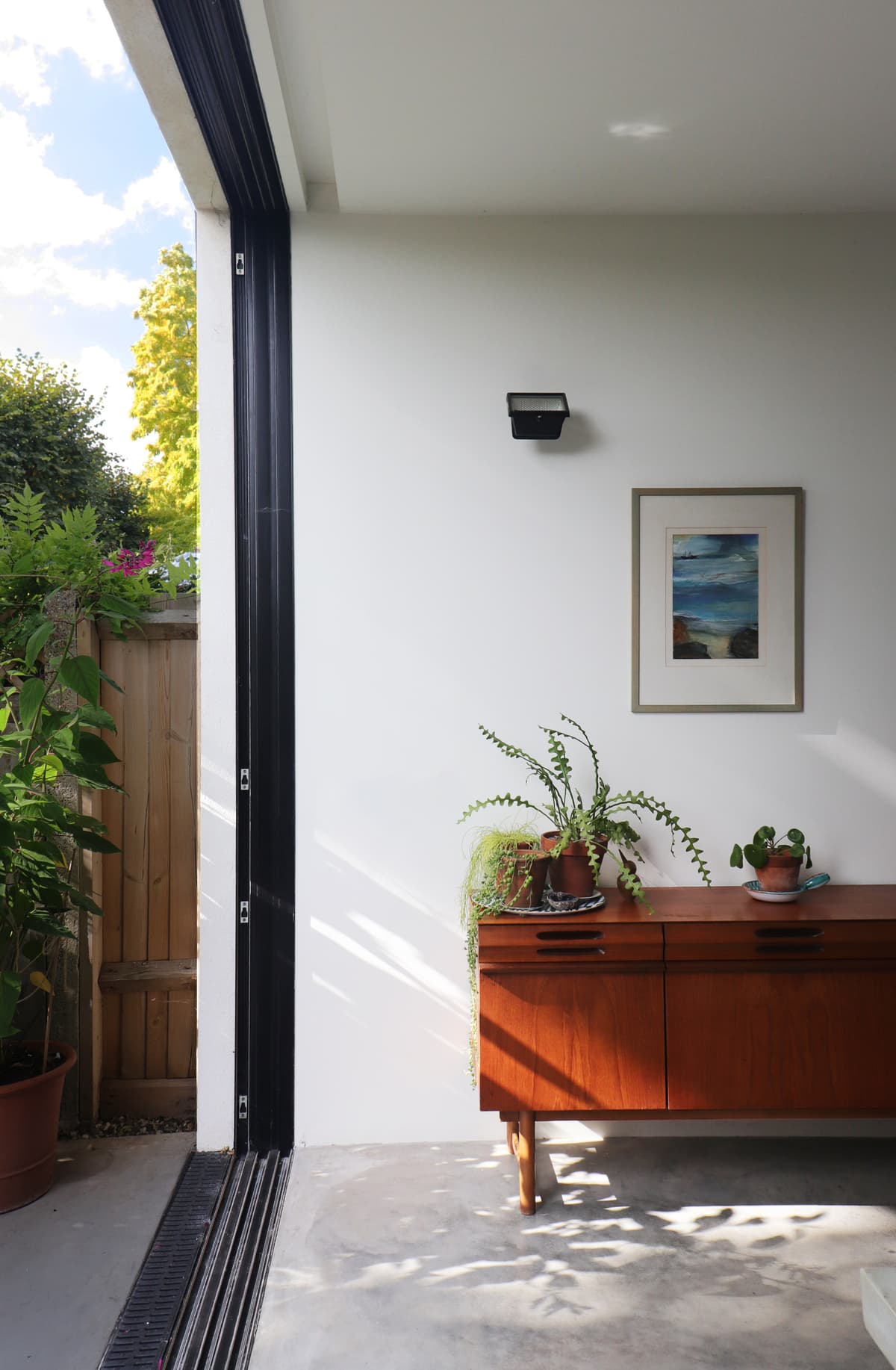 A wide sliding opening connects the dining room and garden terrace at Structuralist House.