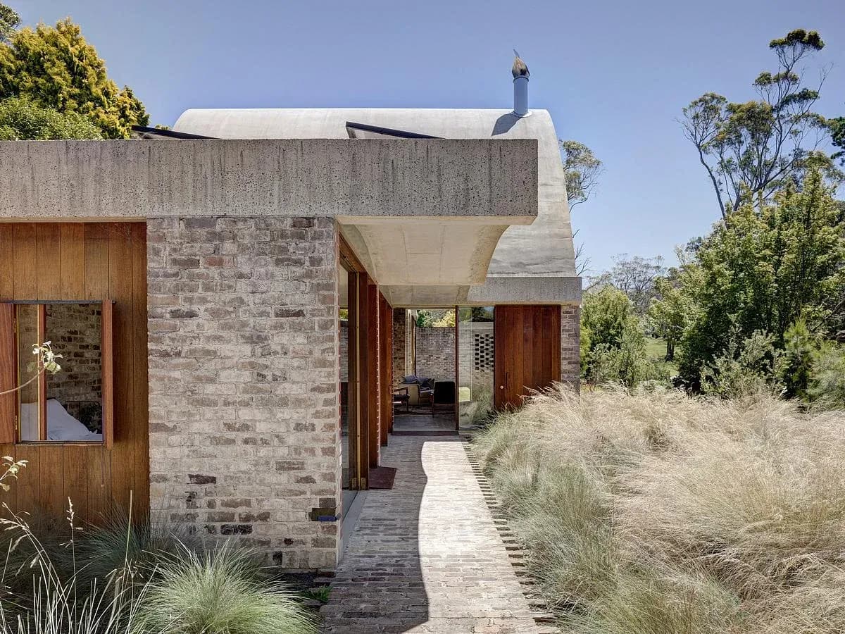 A planted approach leads between brick walls to the house.