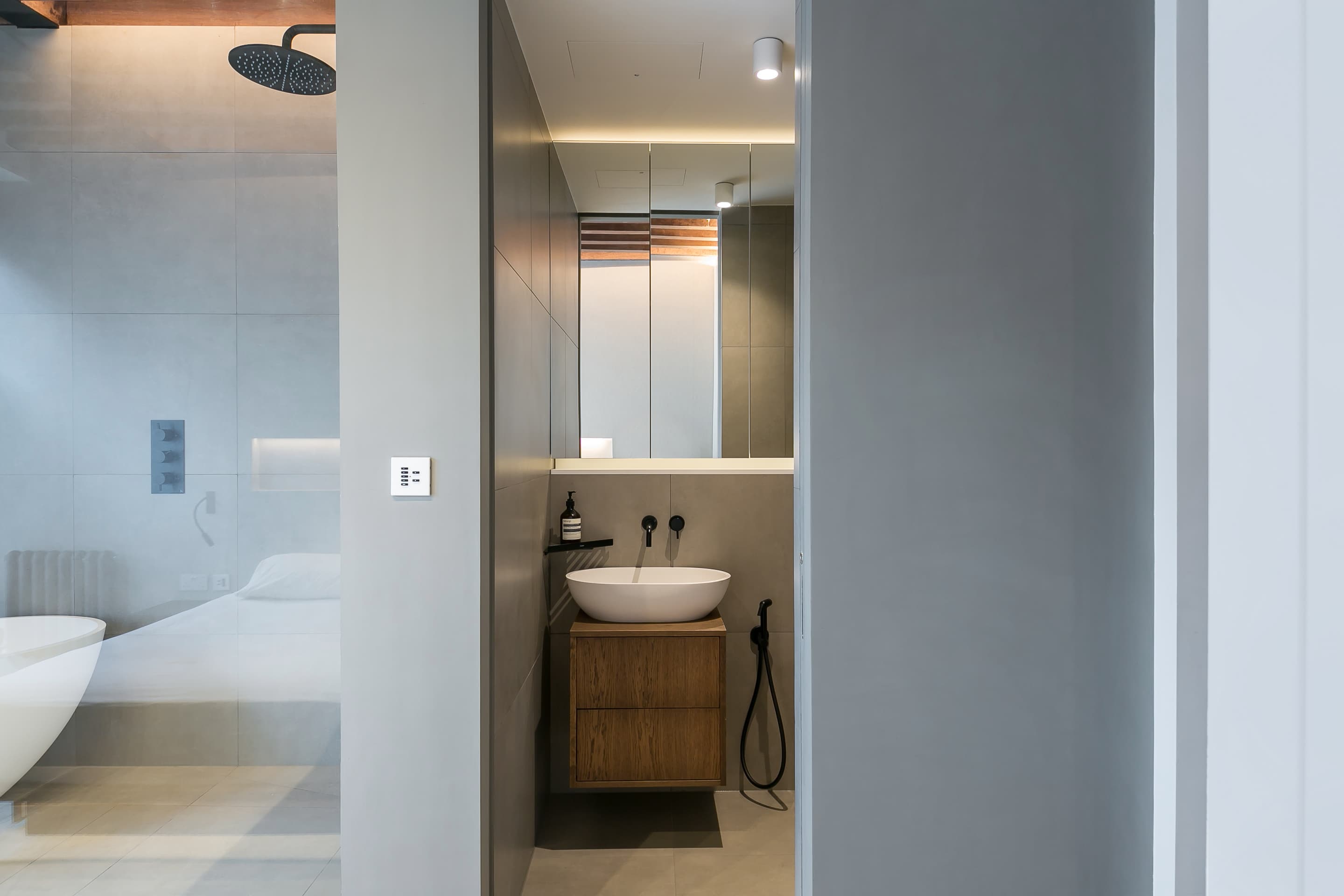 A glazed shower screen and a fitted vanity sit beside the bedroom.