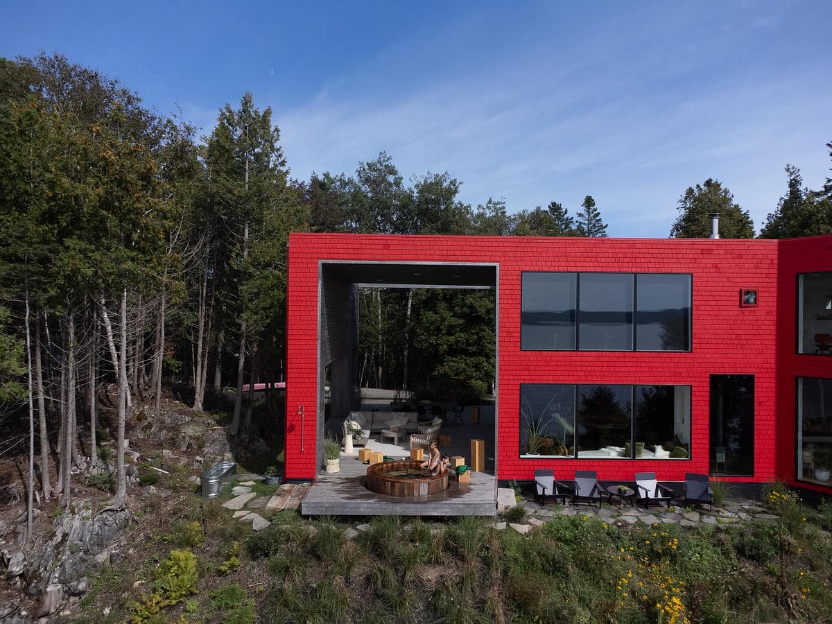 The house sits among trees above its waterfront setting.