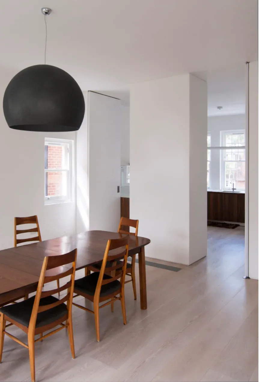 A suspended light marks the dining space beside full-height white joinery.