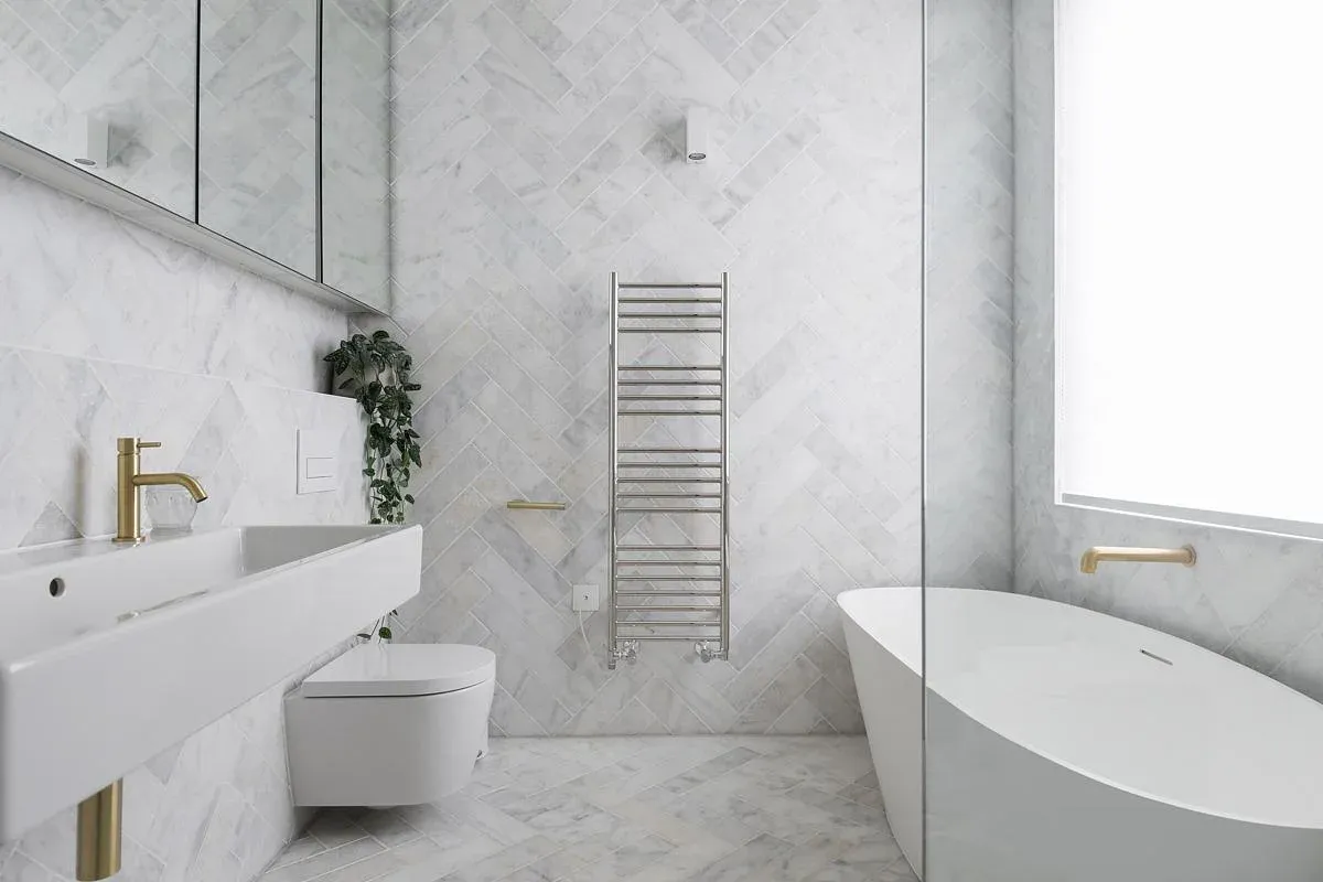 Veined wall and floor finishes surround the freestanding bath.