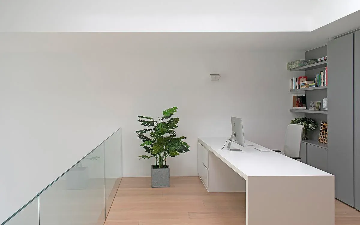 A white desk and built-in shelving occupy the upper-level office.