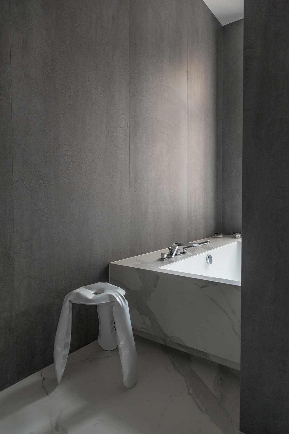 A freestanding bath and concealed light soften the bathroom’s grey surfaces.