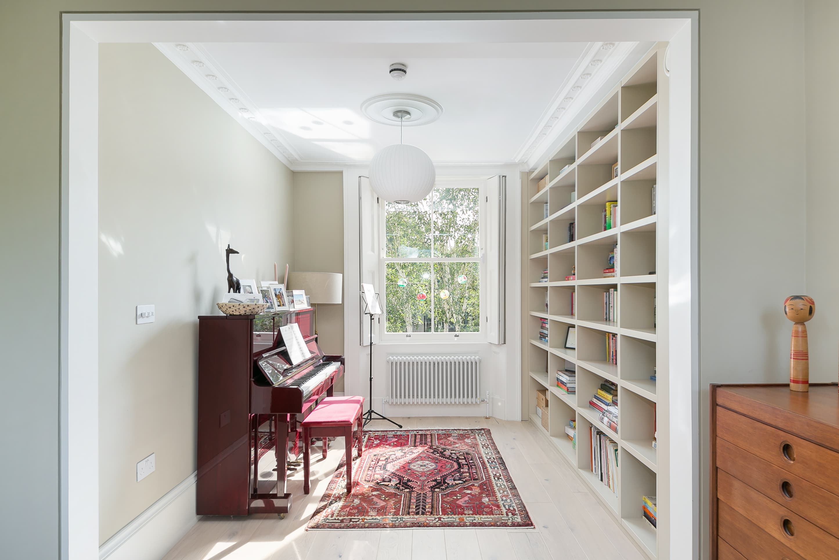 The original front room retains its fireplace, piano and fitted shelving.