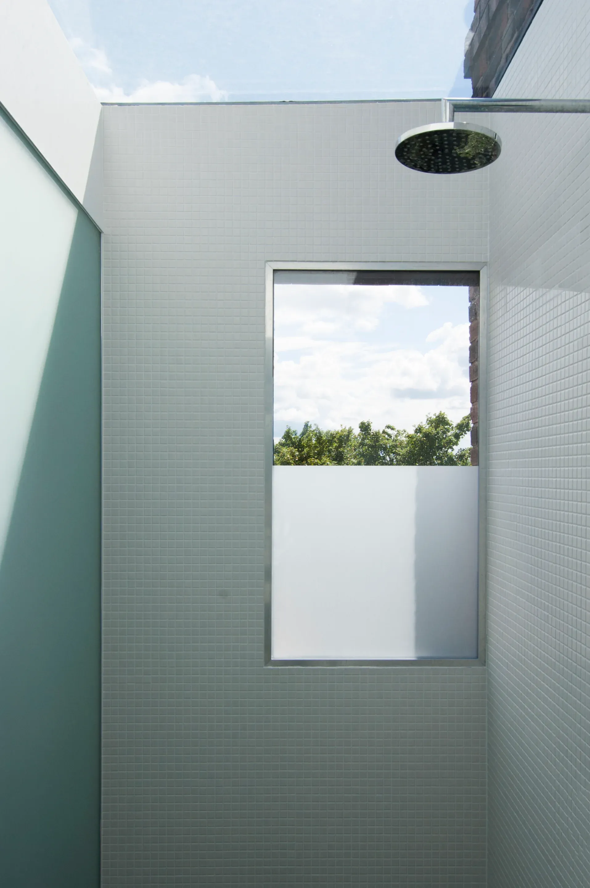 A glazed opening frames the sky above the tiled shower.