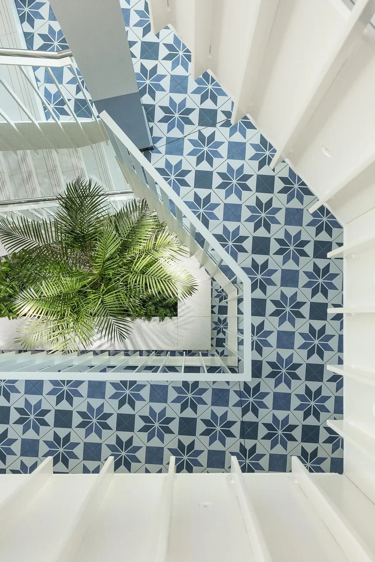 Planting sits at the base of the atrium, seen from the patterned stairs above.