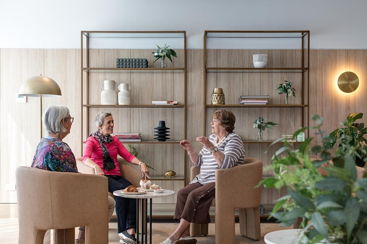Residents gather for tea in a small sitting area.