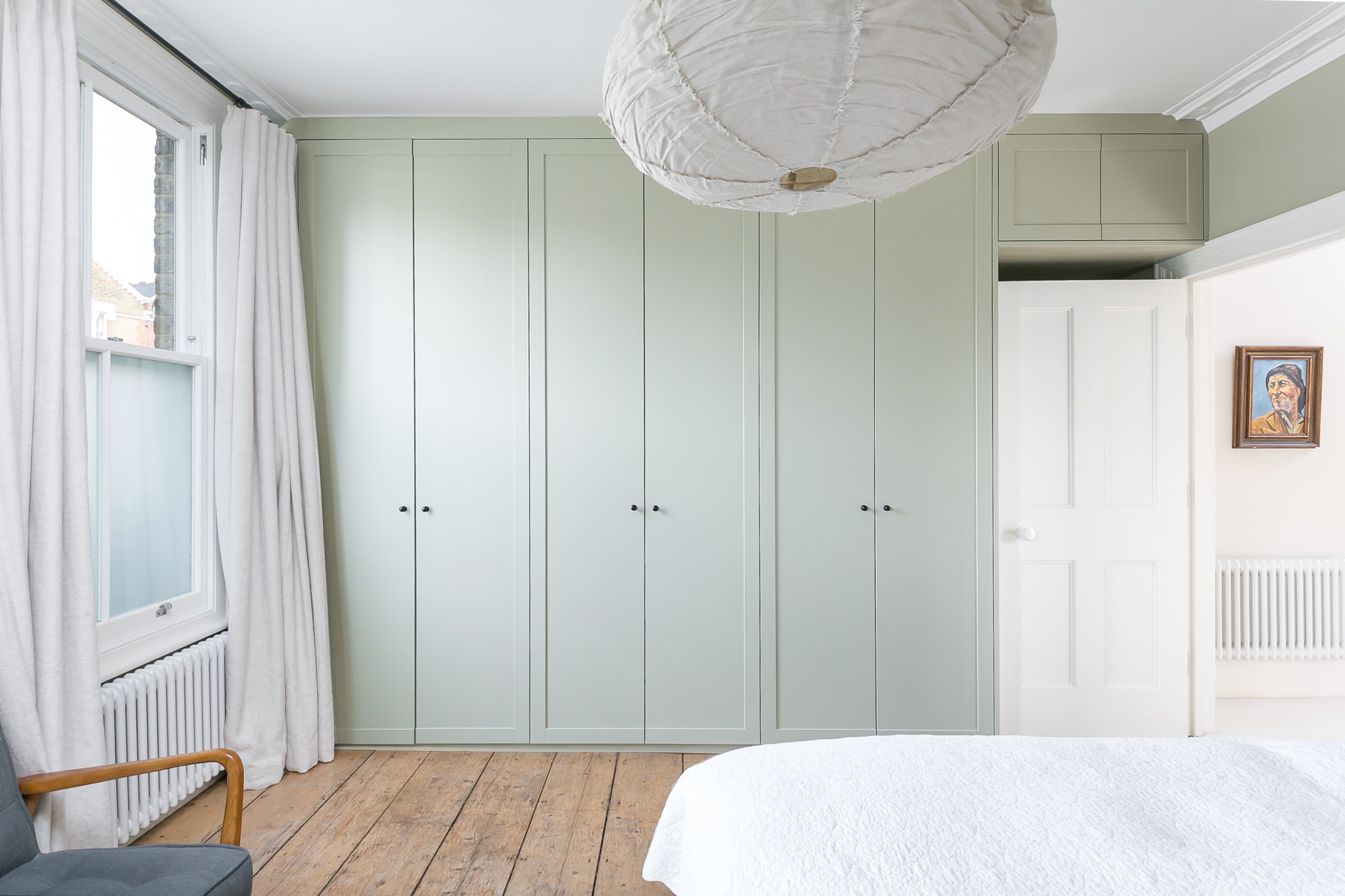 Pale green fitted cupboards line the bedroom wall.
