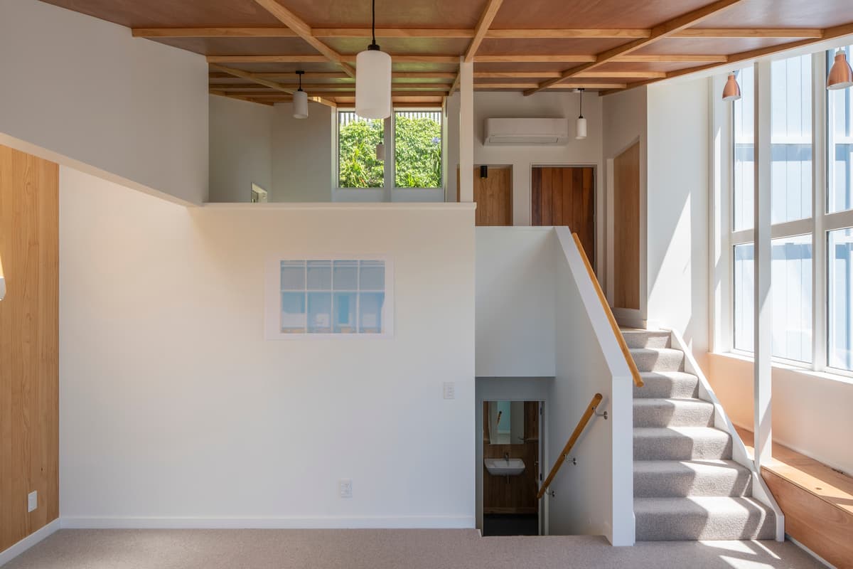 The upper living space opens towards glazing and the stair.