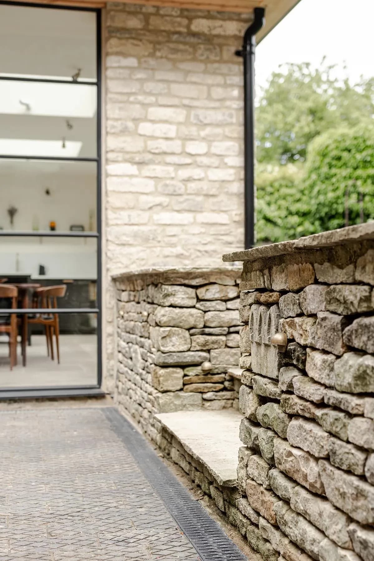 Full-height glazing meets the dry-stone garden wall at the corner of the extension.