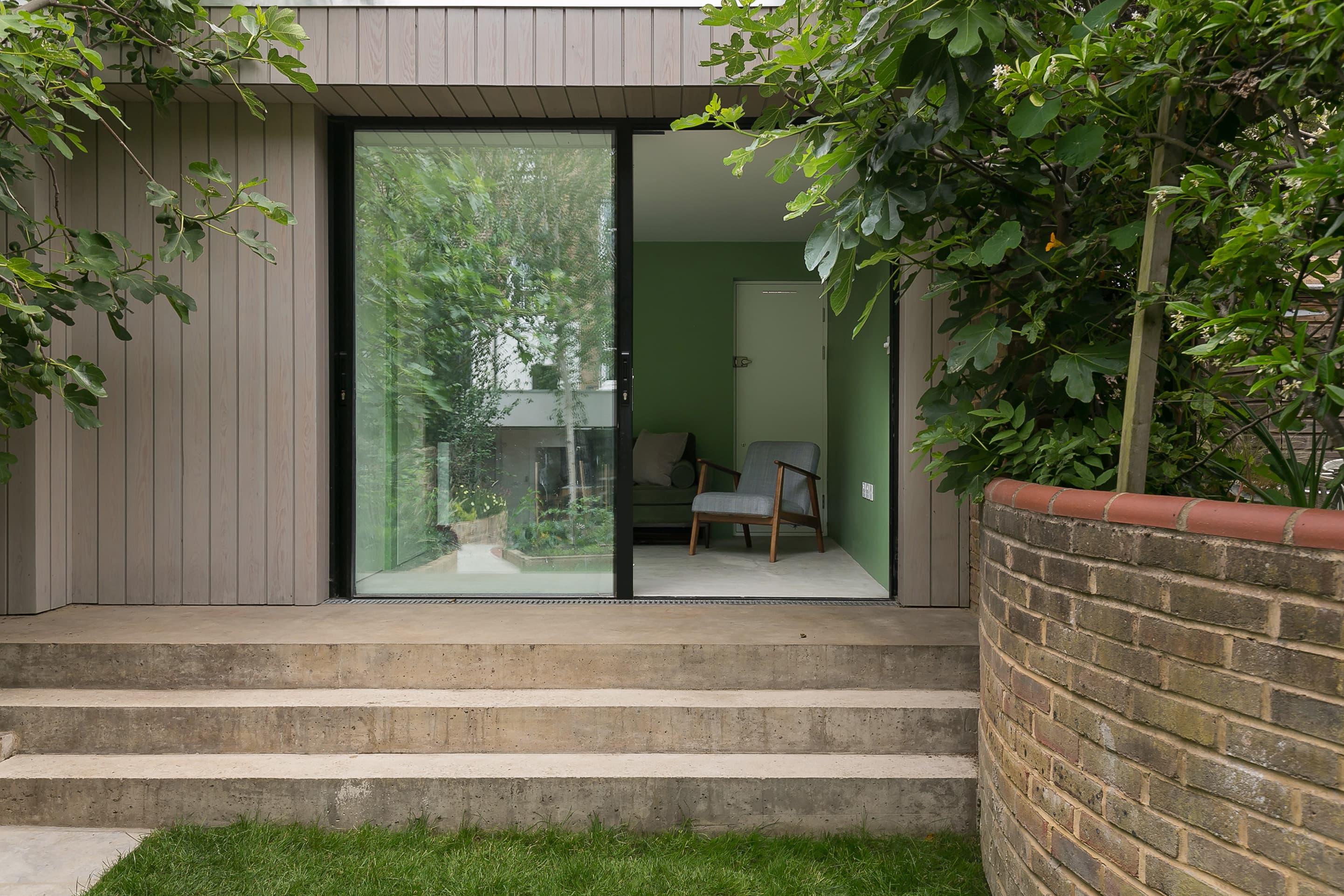 Steps lead to the glazed entrance of the timber-clad garden studio.