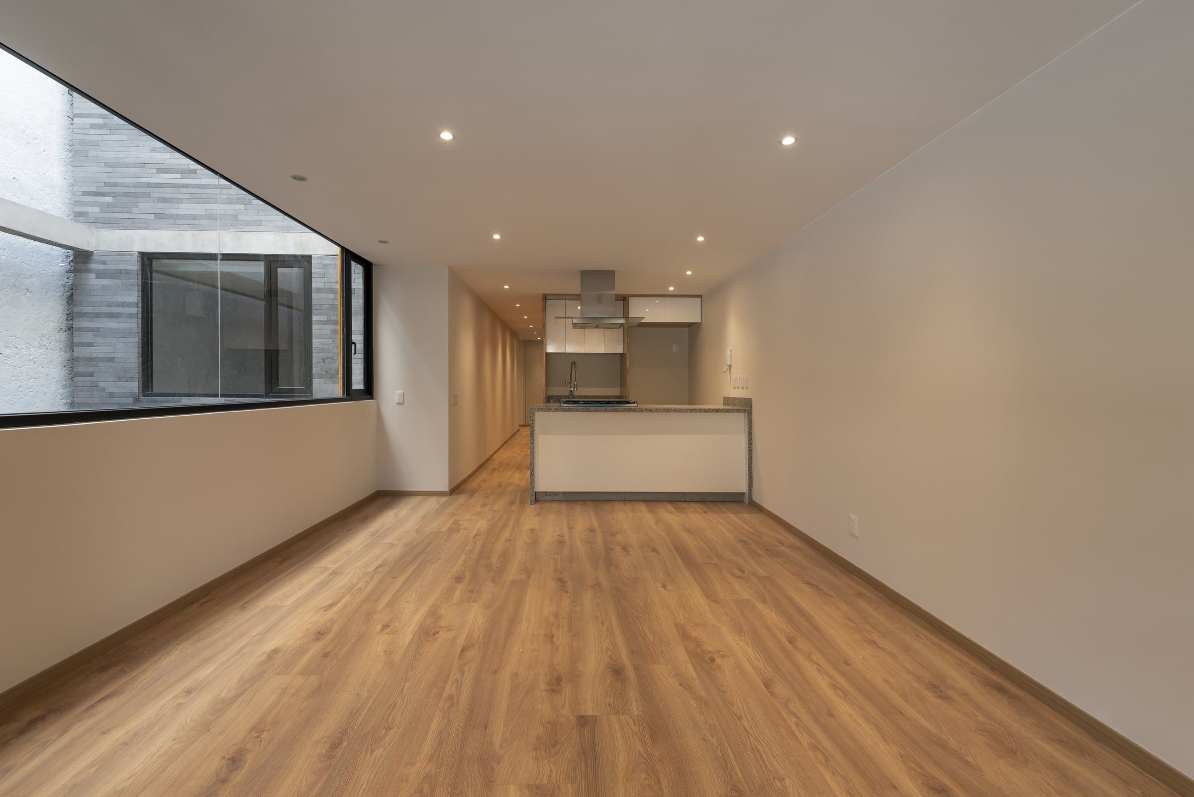 A long living and dining room pairs timber flooring with a concrete ceiling.