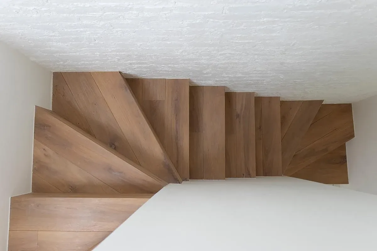 Timber stair treads turn beneath a textured white wall at Diorama 2.