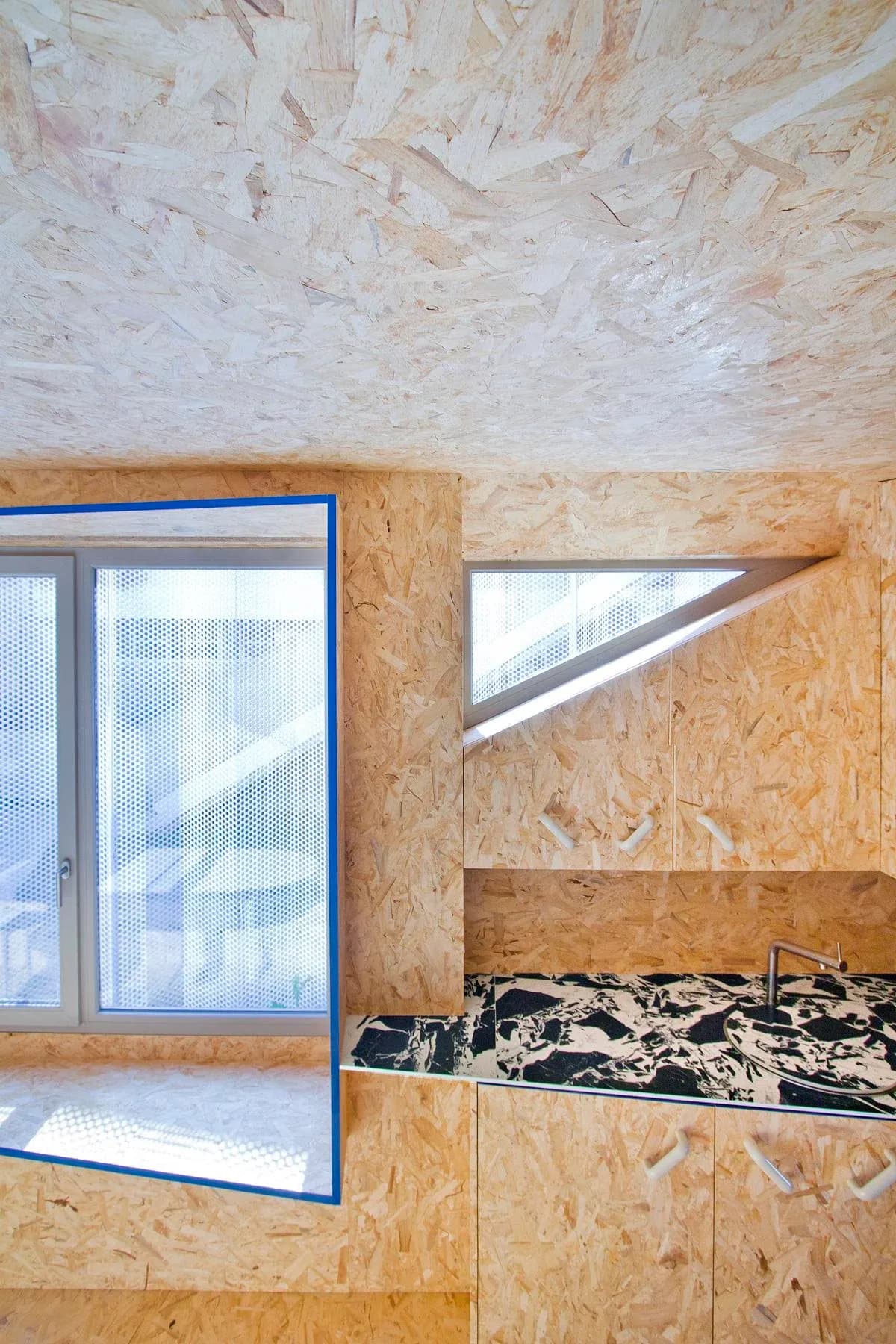 The fitted kitchen combines OSB surfaces with a patterned worktop.