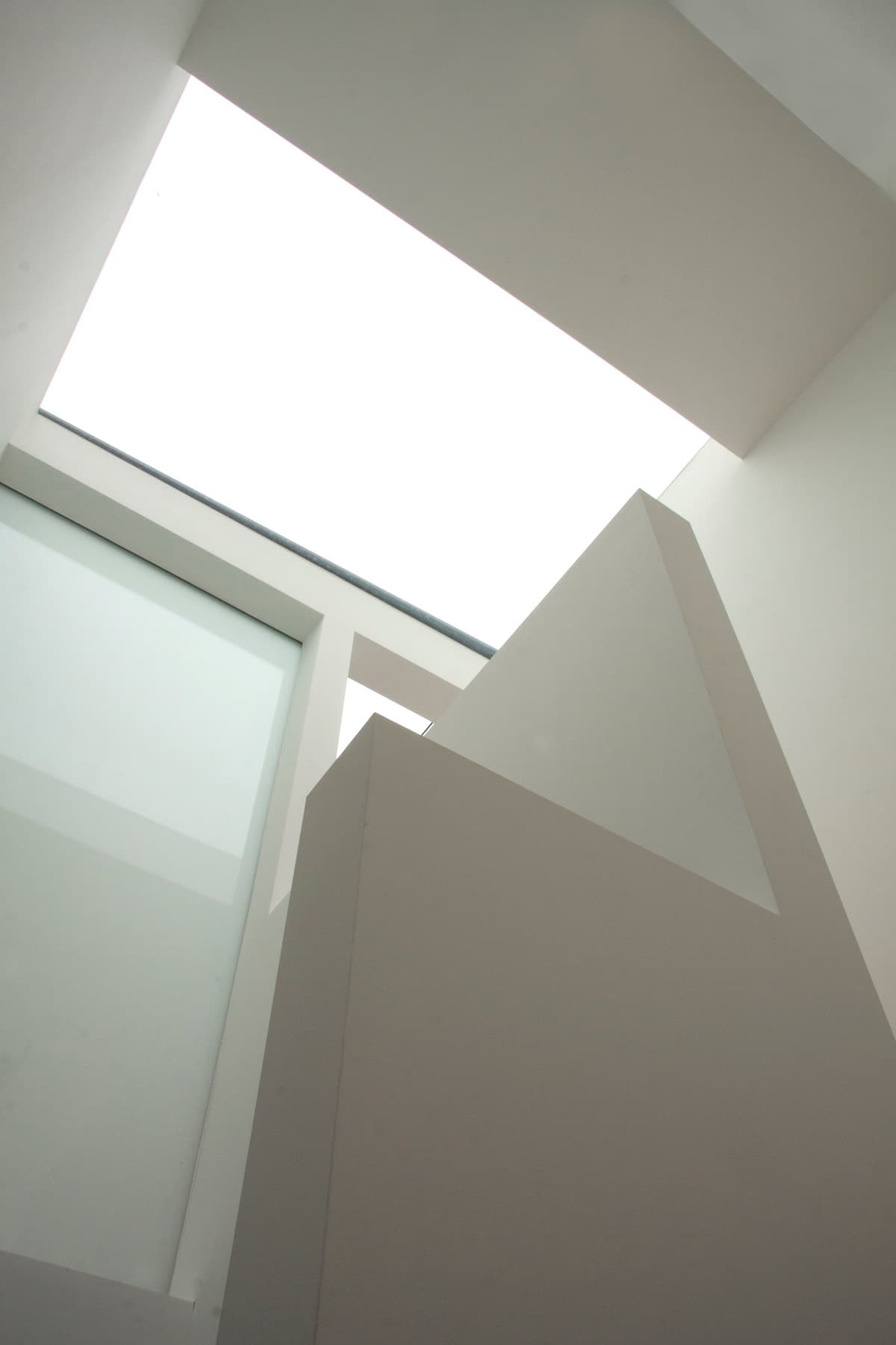 A rooflight illuminates the white planes of the upper stairwell at Vertical Intersect.
