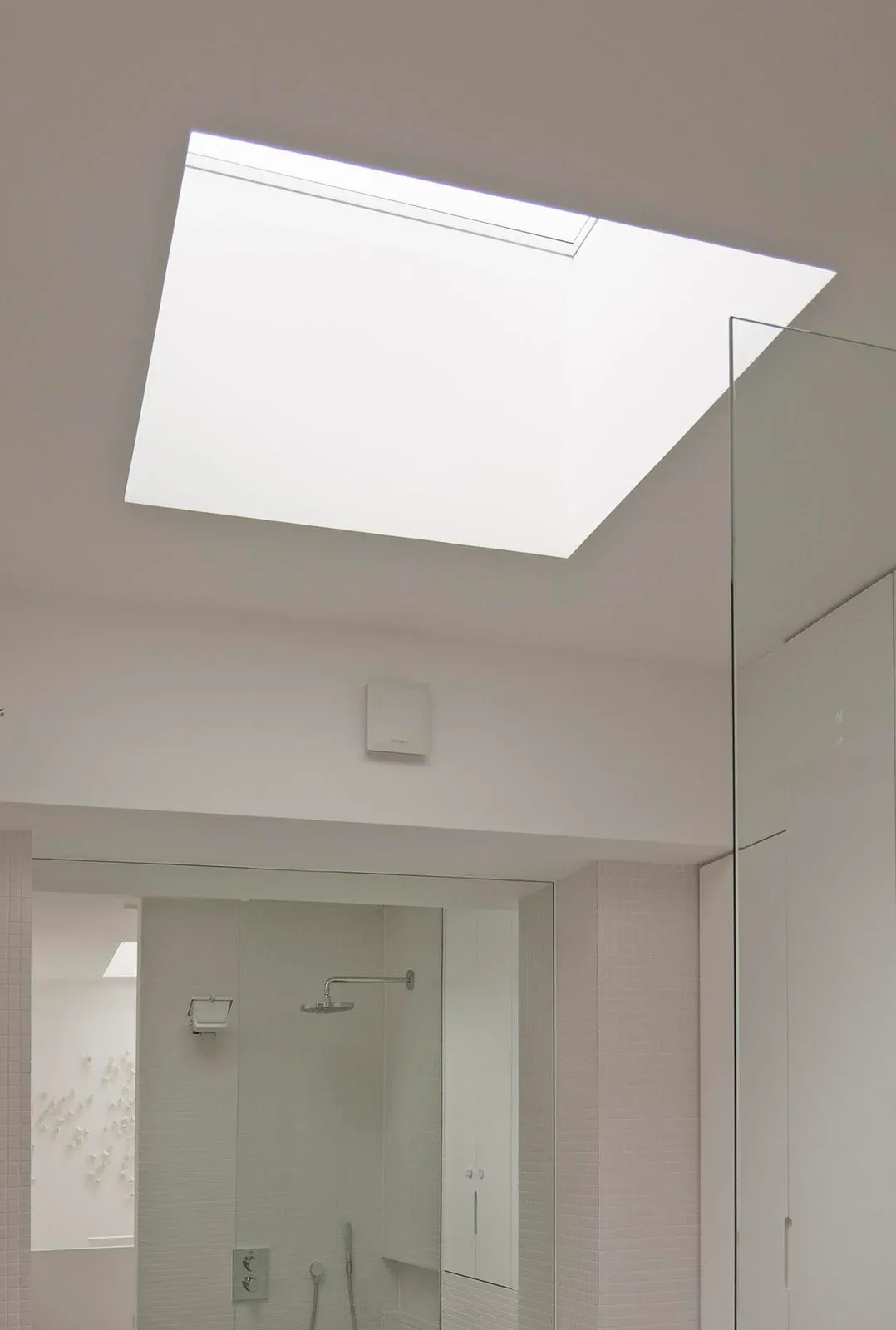 A rooflight brings daylight into a white bathroom at Modern Terrace.