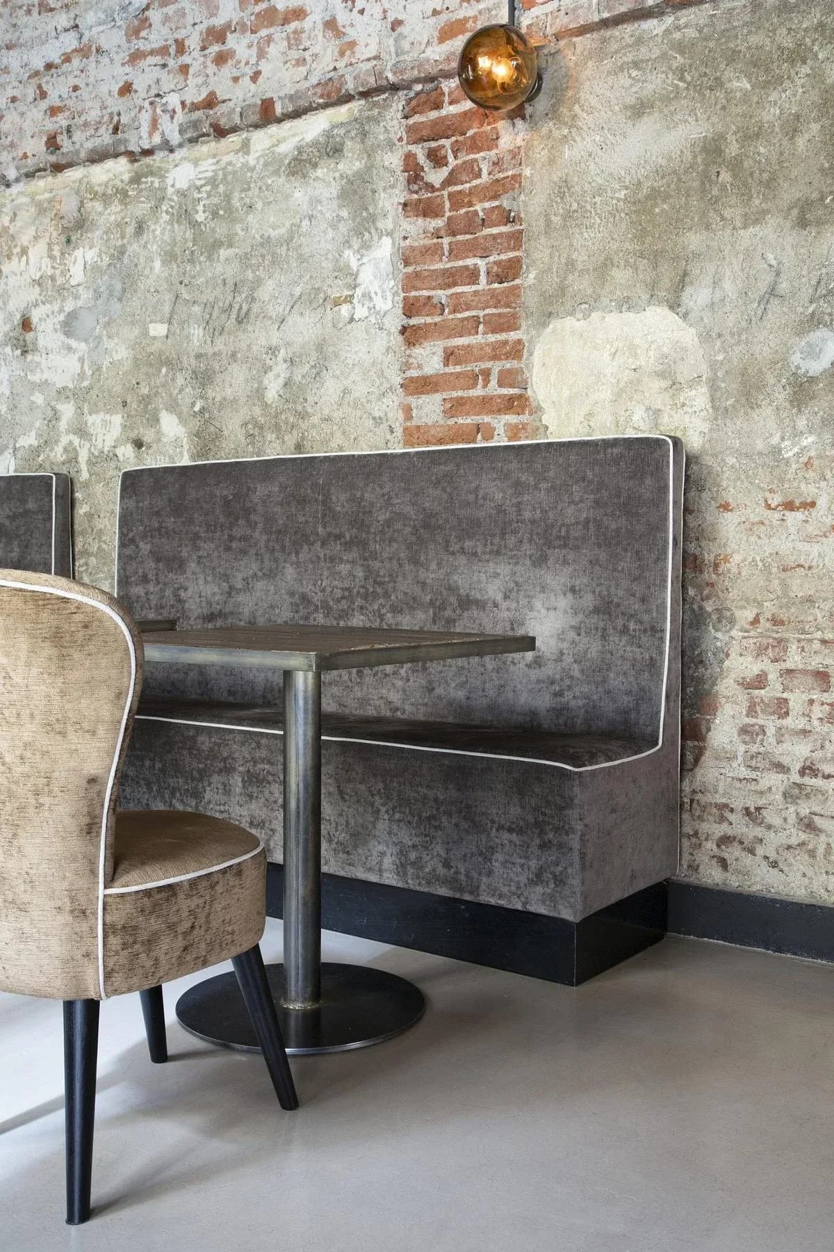 A metal-framed table and upholstered bench meet the existing brick wall.