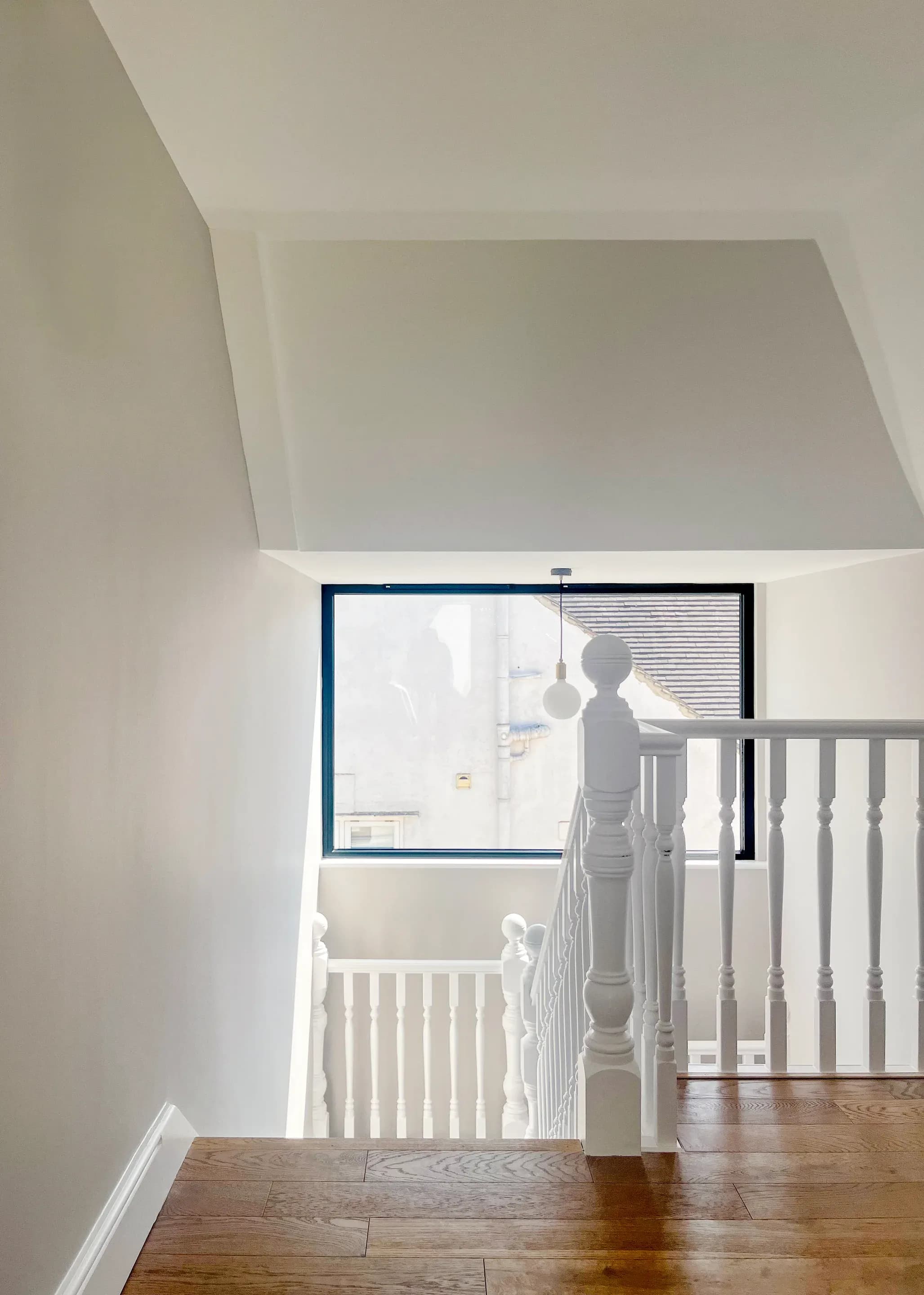 A large landing window frames the neighbouring house beside the retained stair.