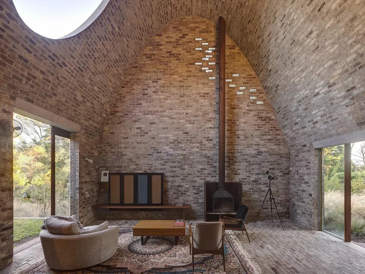 An elliptical skylight opens above the home’s parabolic brick vault.