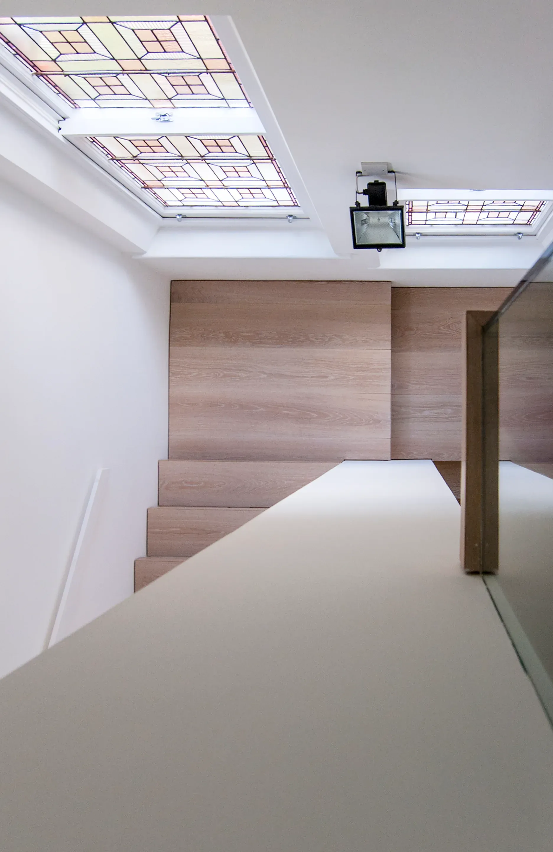 The view down the stair reveals retained stained glass beside the new timber work.
