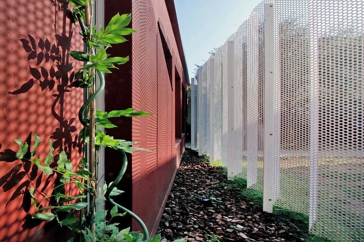 The triangular garden separates the screen from the earth-toned facade.