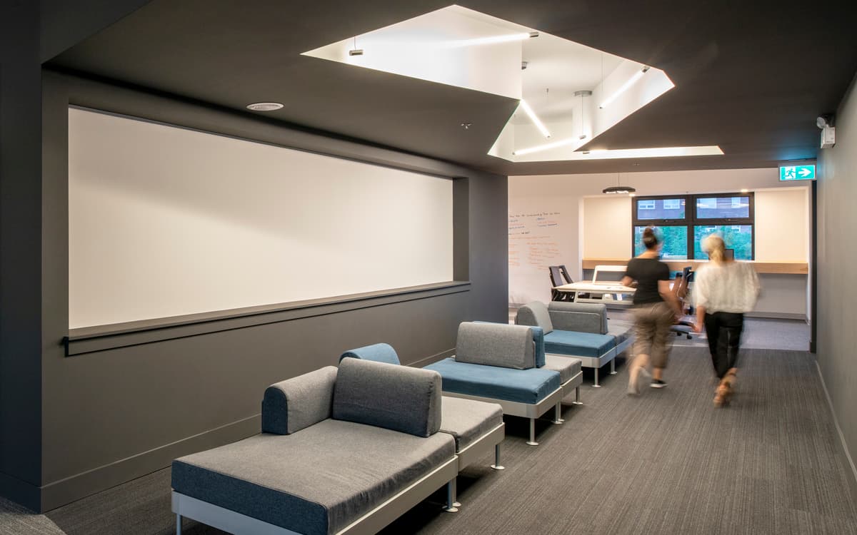 Soft seating creates an informal gathering space beside a large screen.