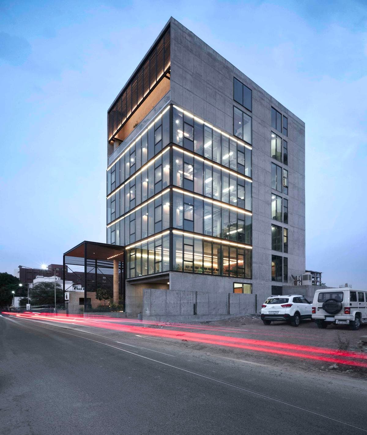 The glazed elevations seen from the street at dusk.