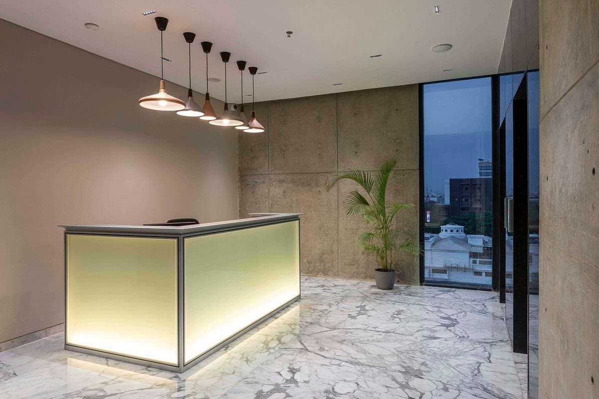 An illuminated reception desk sits against exposed concrete.