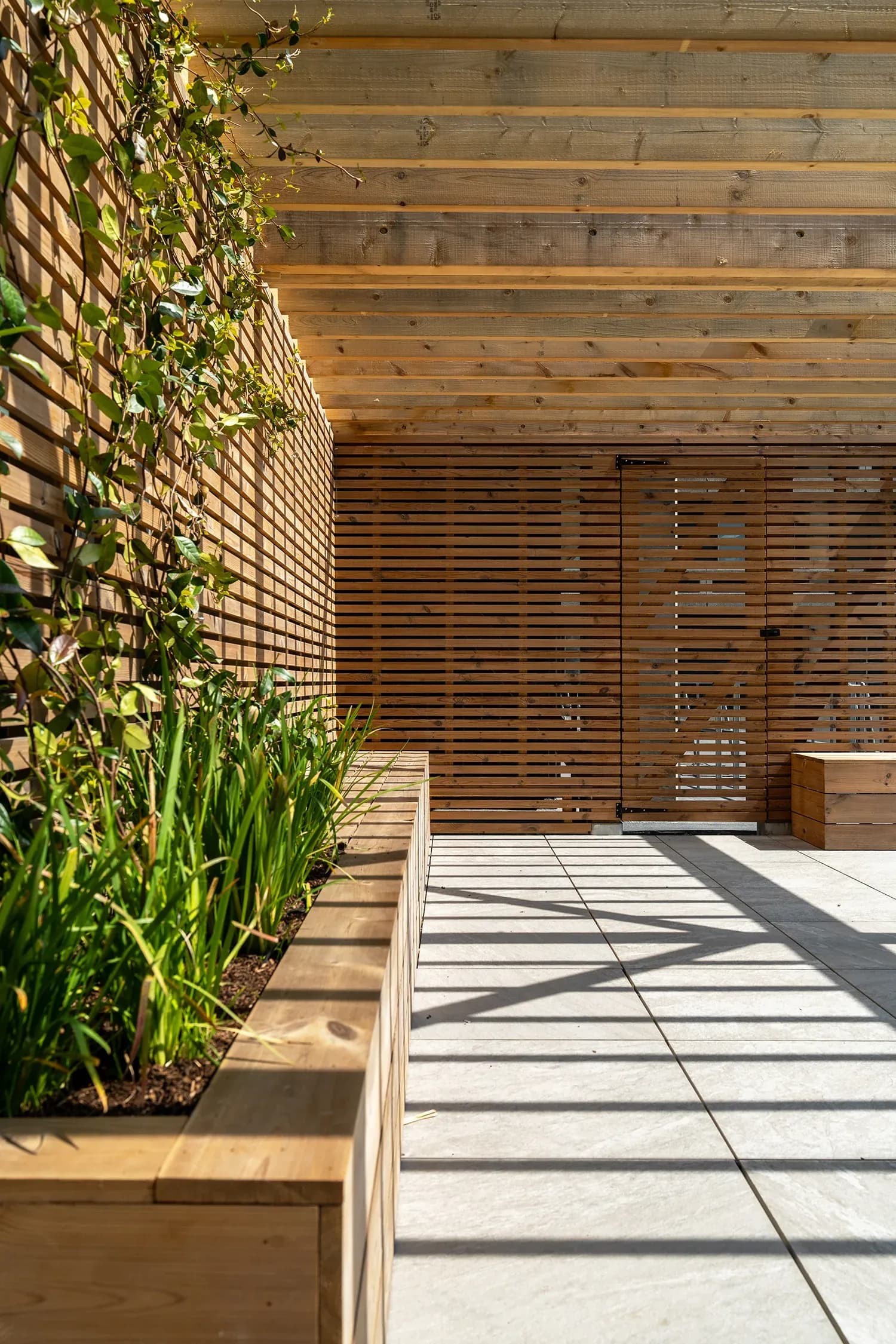 Timber sun shading shelters the seating area at the end of the garden.