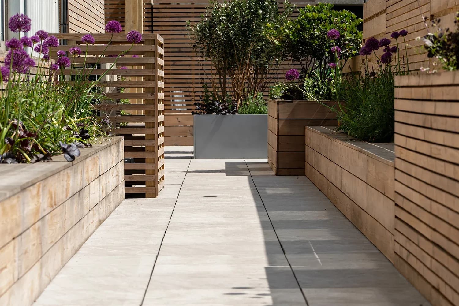 Overlapping planters and screens mark a threshold between garden spaces.