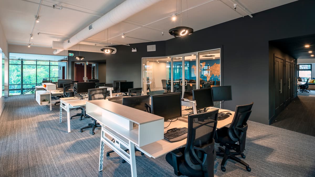 Open workstations sit beside glazed rooms and shared window seating.