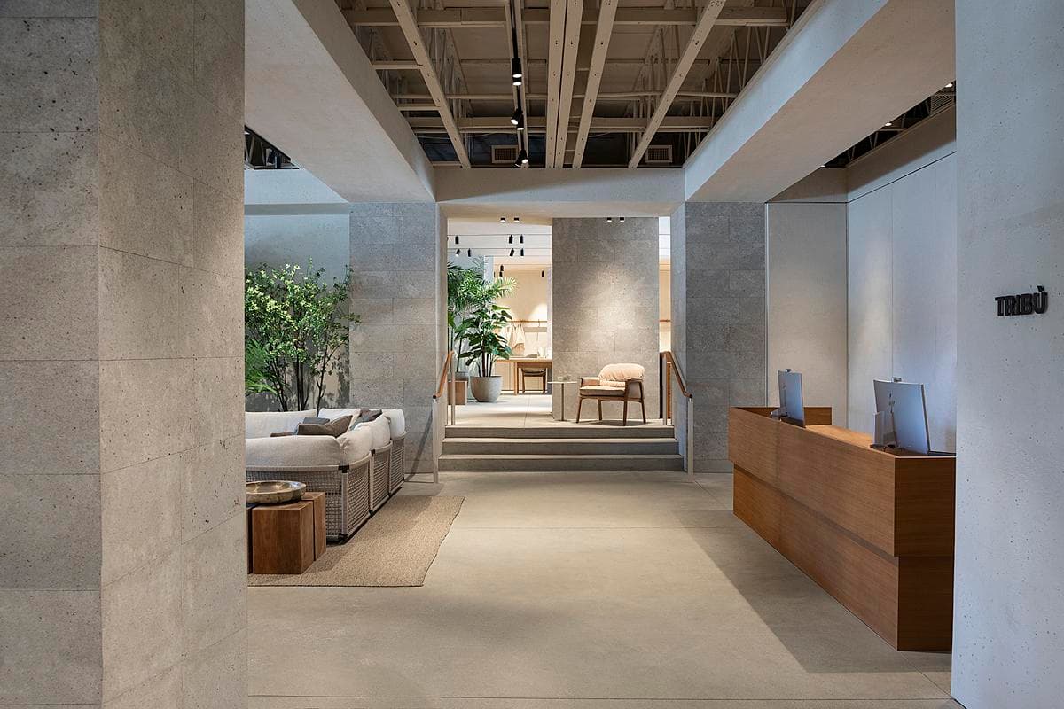 Concrete columns and timber reception furniture frame the route through the showroom.