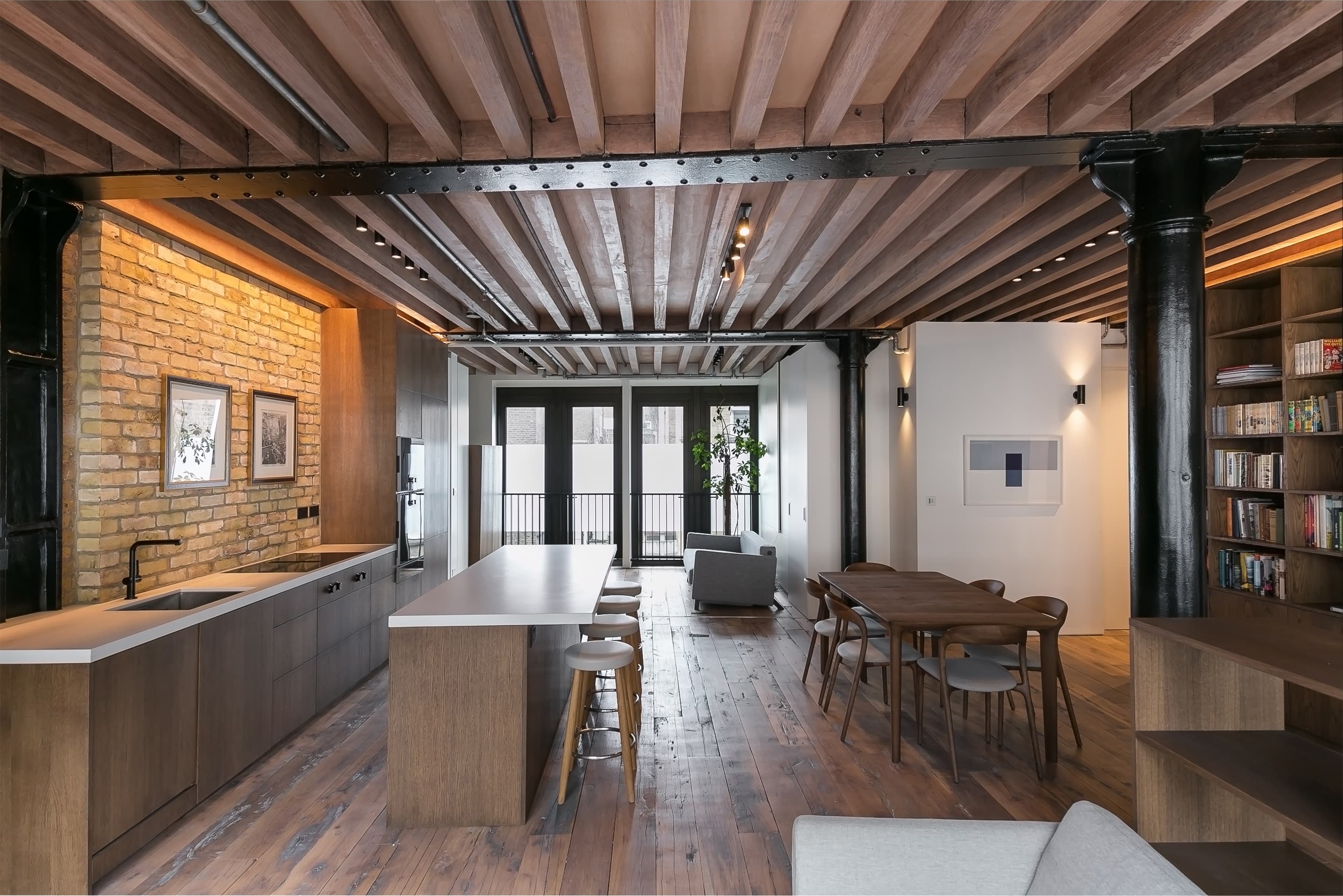 The kitchen island sits beneath retained timber joists and steelwork.