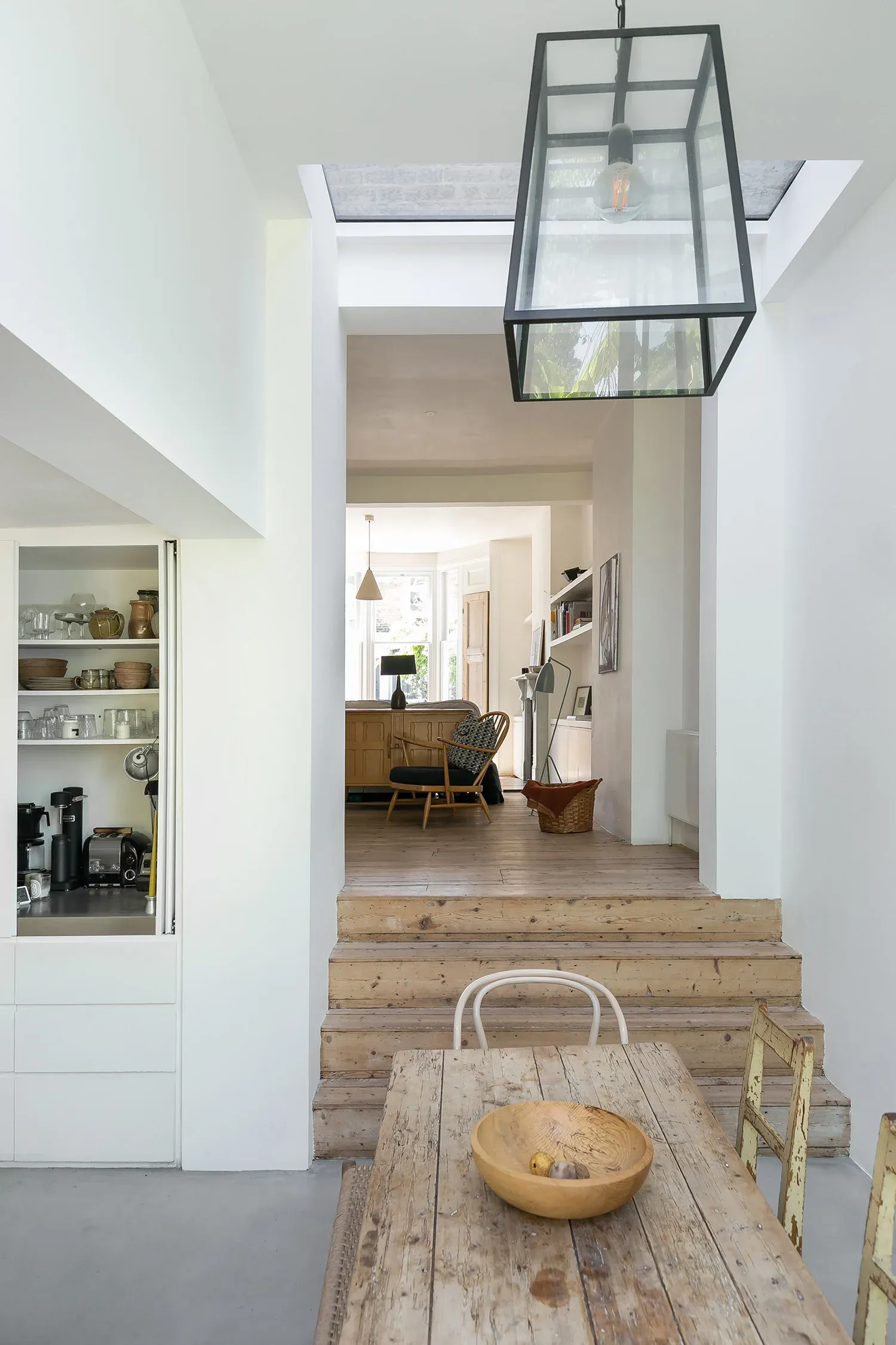 A rooflight draws daylight into the dining area beside the timber steps.