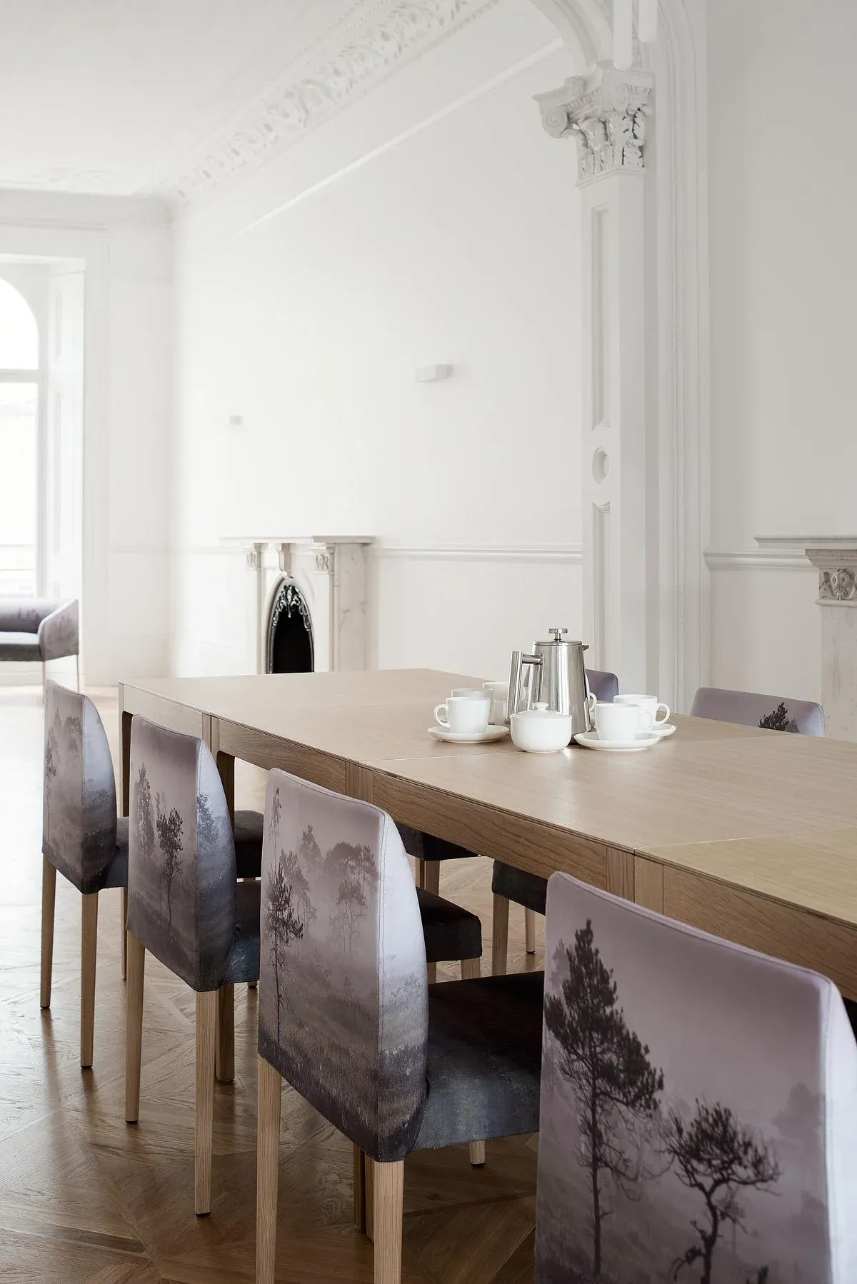 Landscape-printed dining chairs line a timber table.