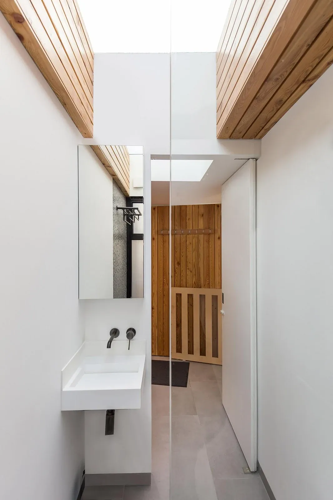 Washroom with a rooflight and timber doors at Split Space.